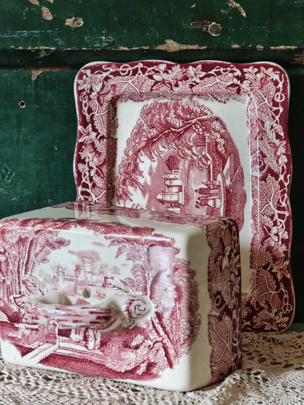 A Masons Vista ceramic butter dish with a matching rectangular plate, both featuring a pink and white toile de Jouy landscape pattern.