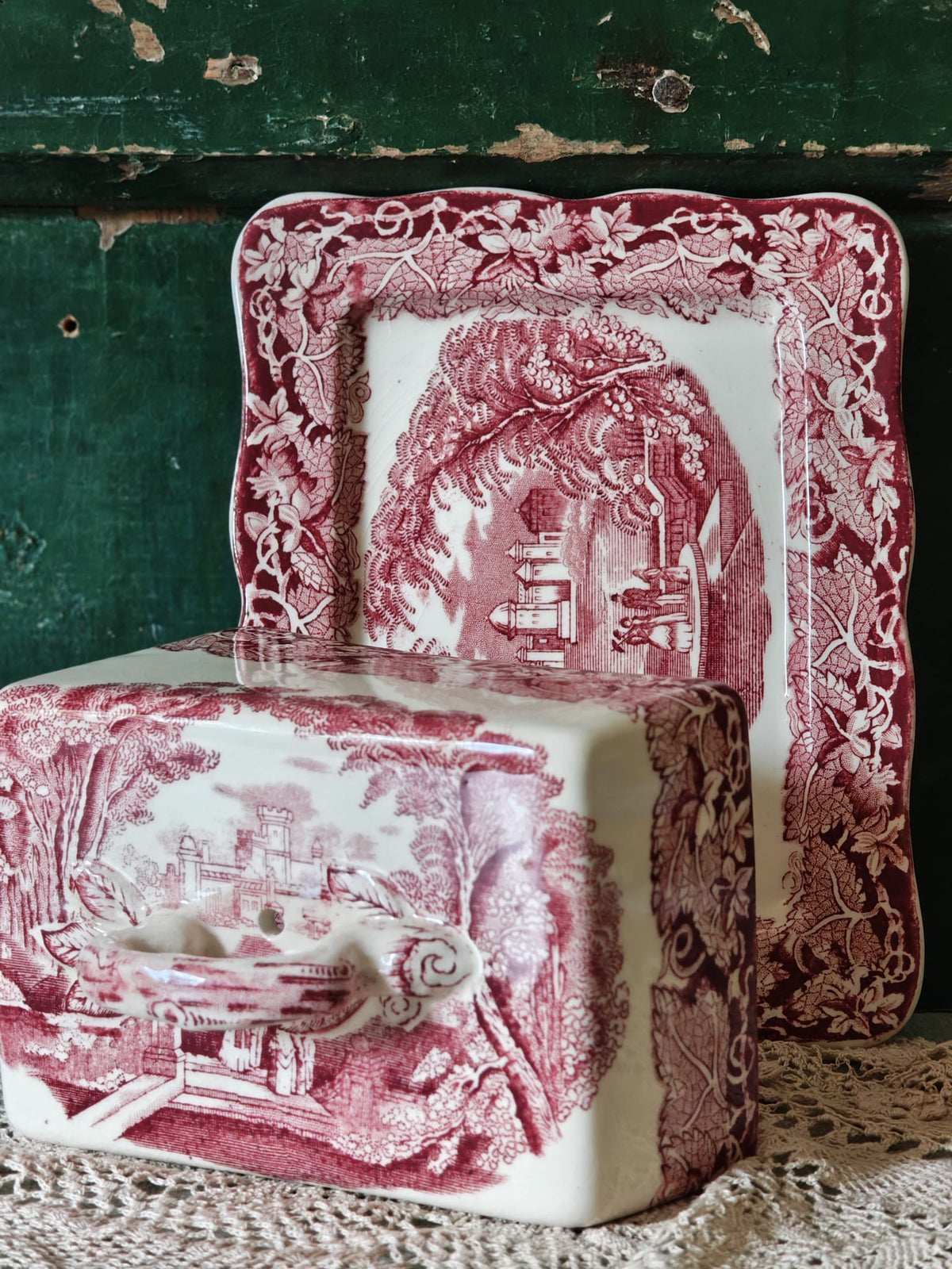 A Masons Vista ceramic butter dish with a matching rectangular plate, both featuring a pink and white toile de Jouy landscape pattern.