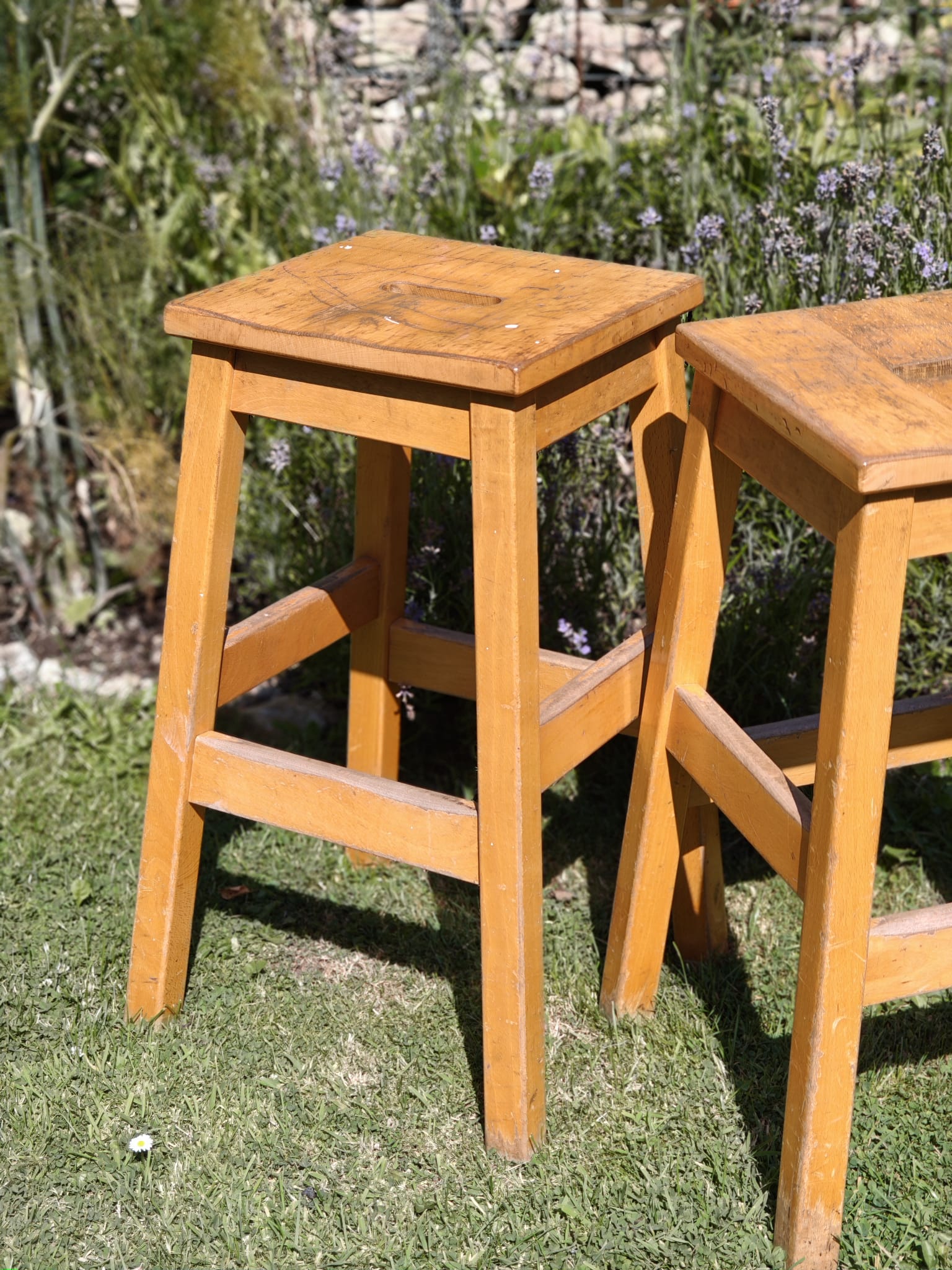 Two wooden lab stools with square seats and straight legs