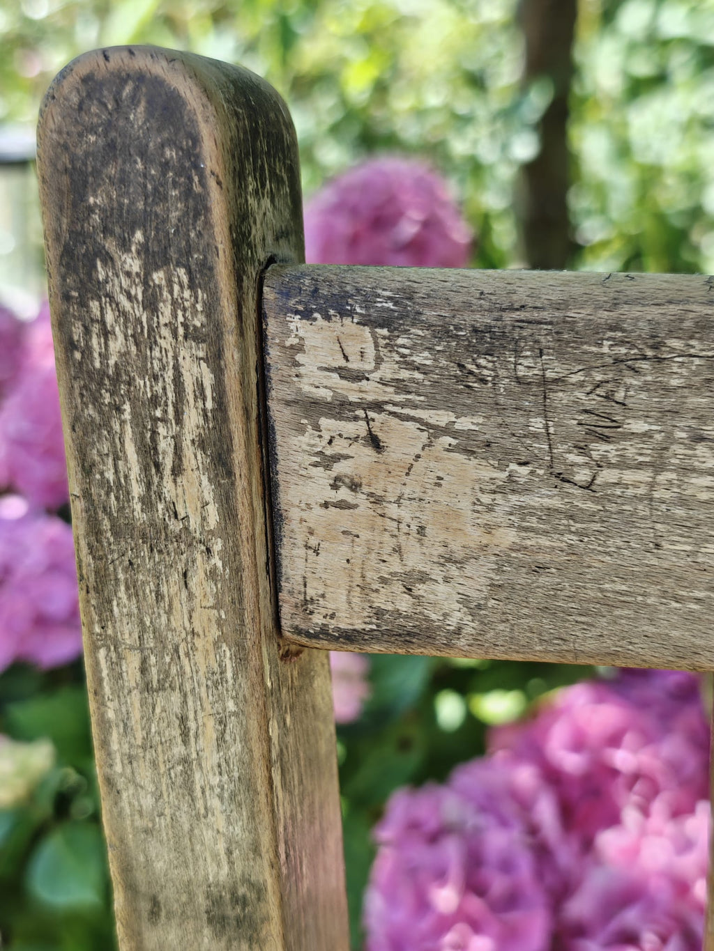 A close-up of a weathered wooden chair corner 
