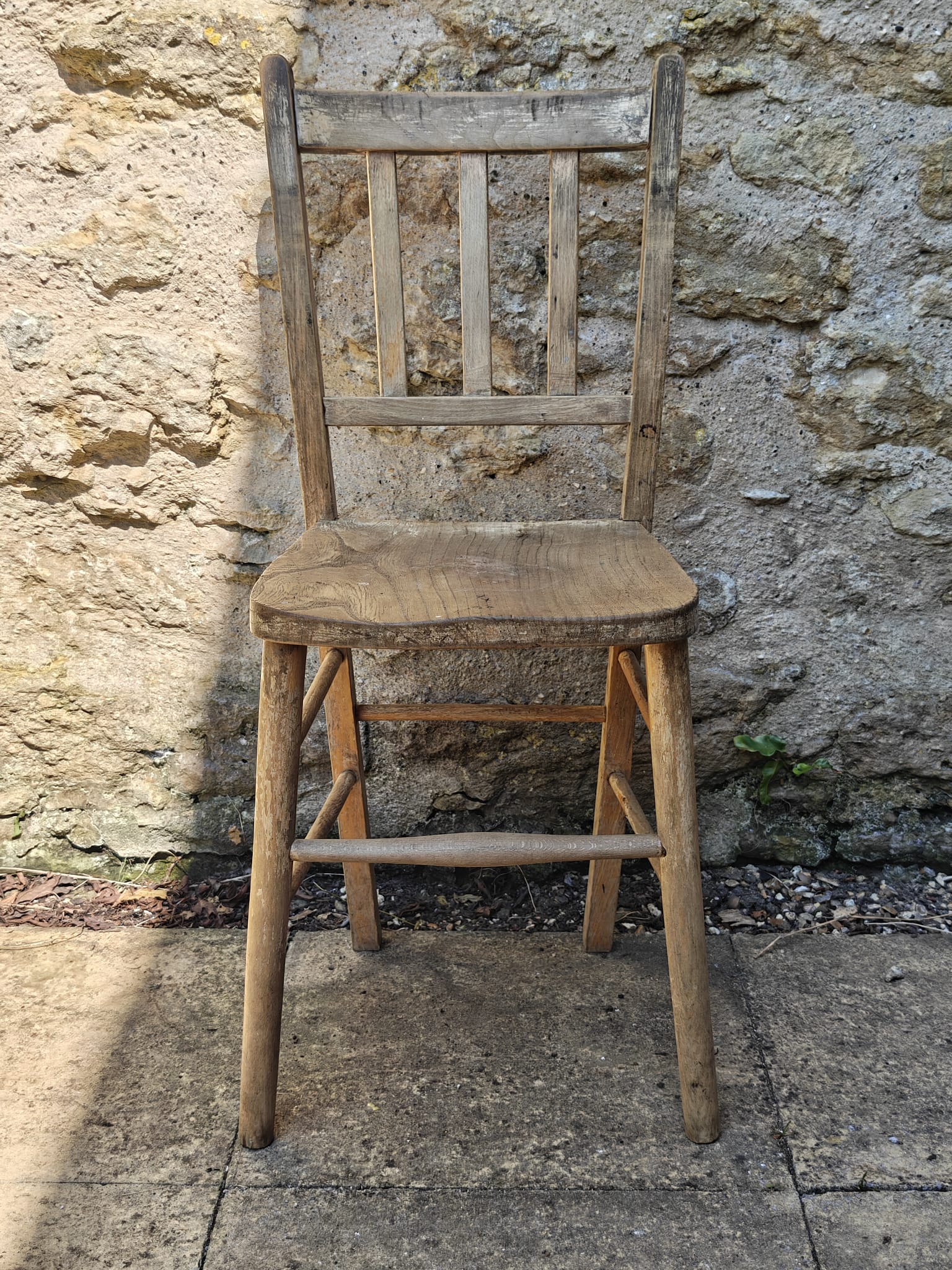A rustic wooden chair with a slatted backrest and a thick seat