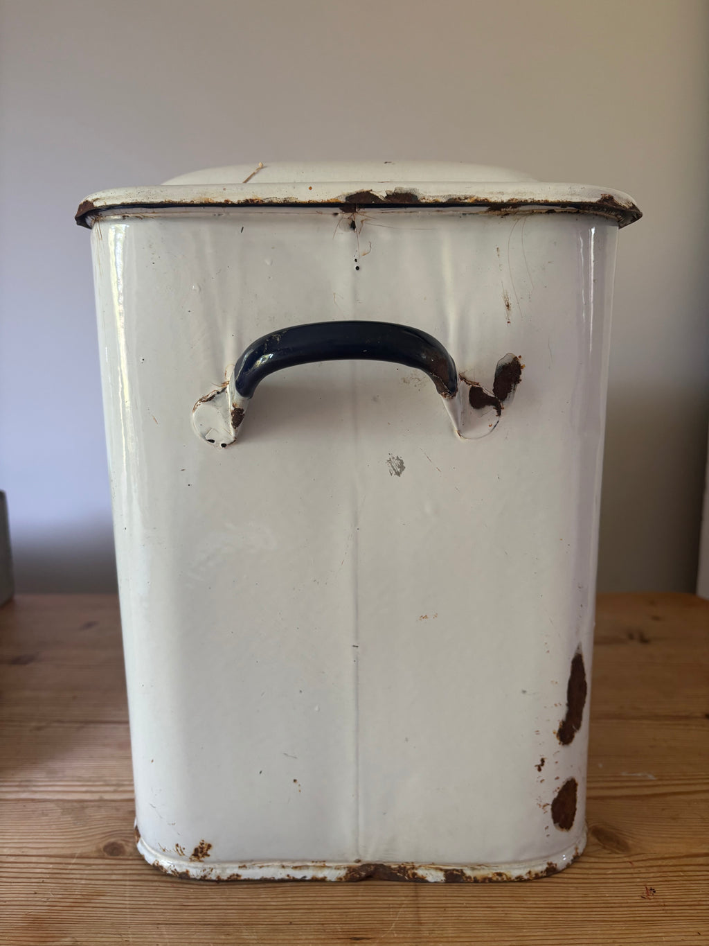 A vintage white enamel storage canister with a dark blue handle.