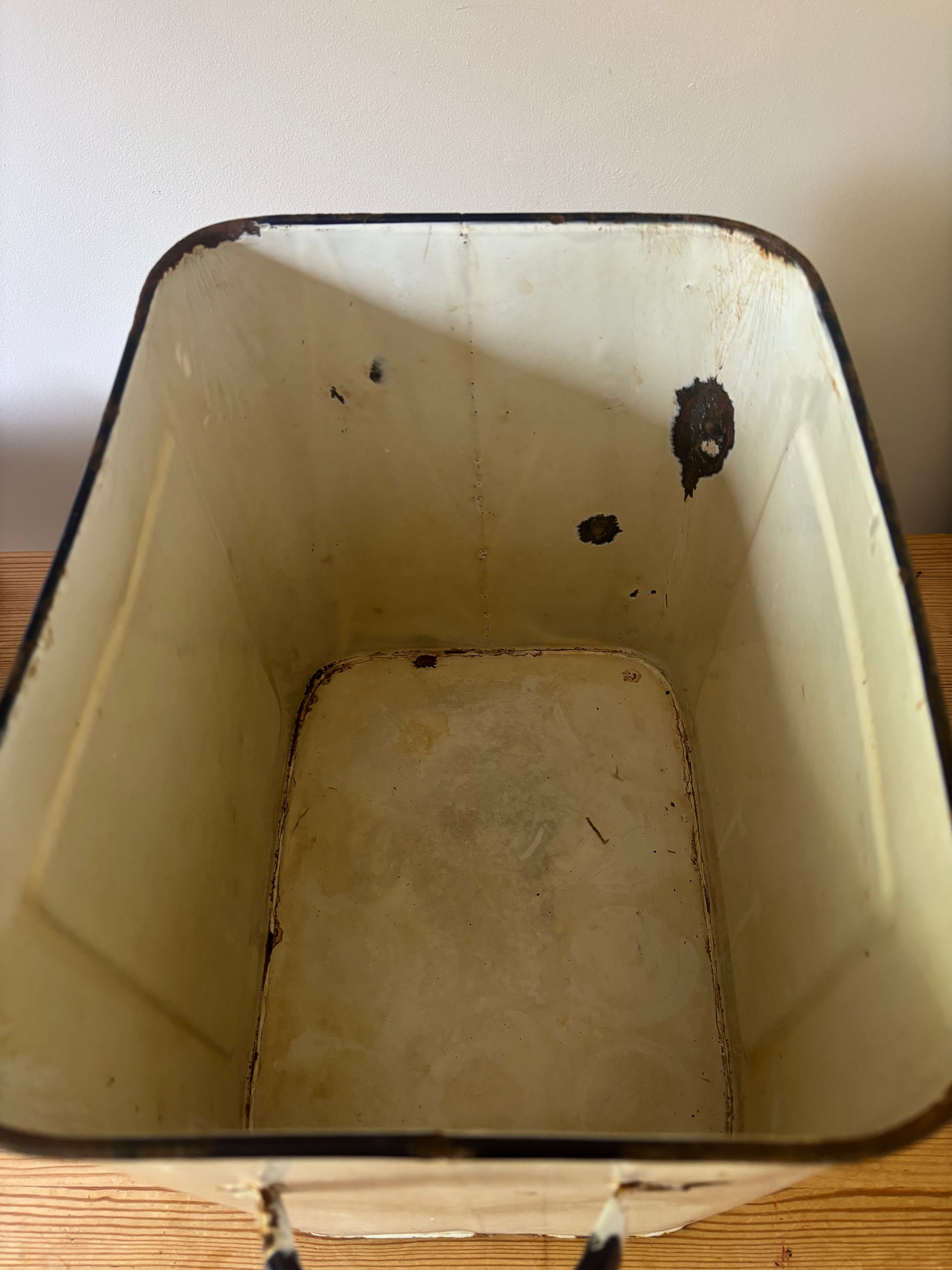 The inside of a vintage emanmel bread bin.