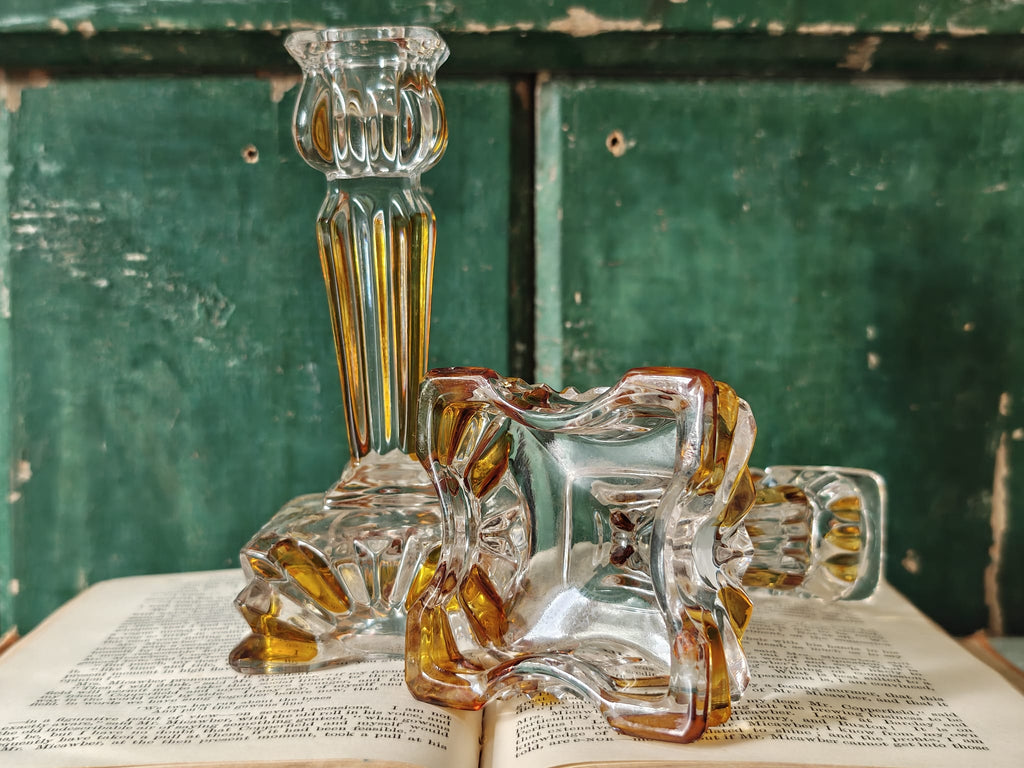A pair of clear glass candleholders with amber-yellow tinted edges.
