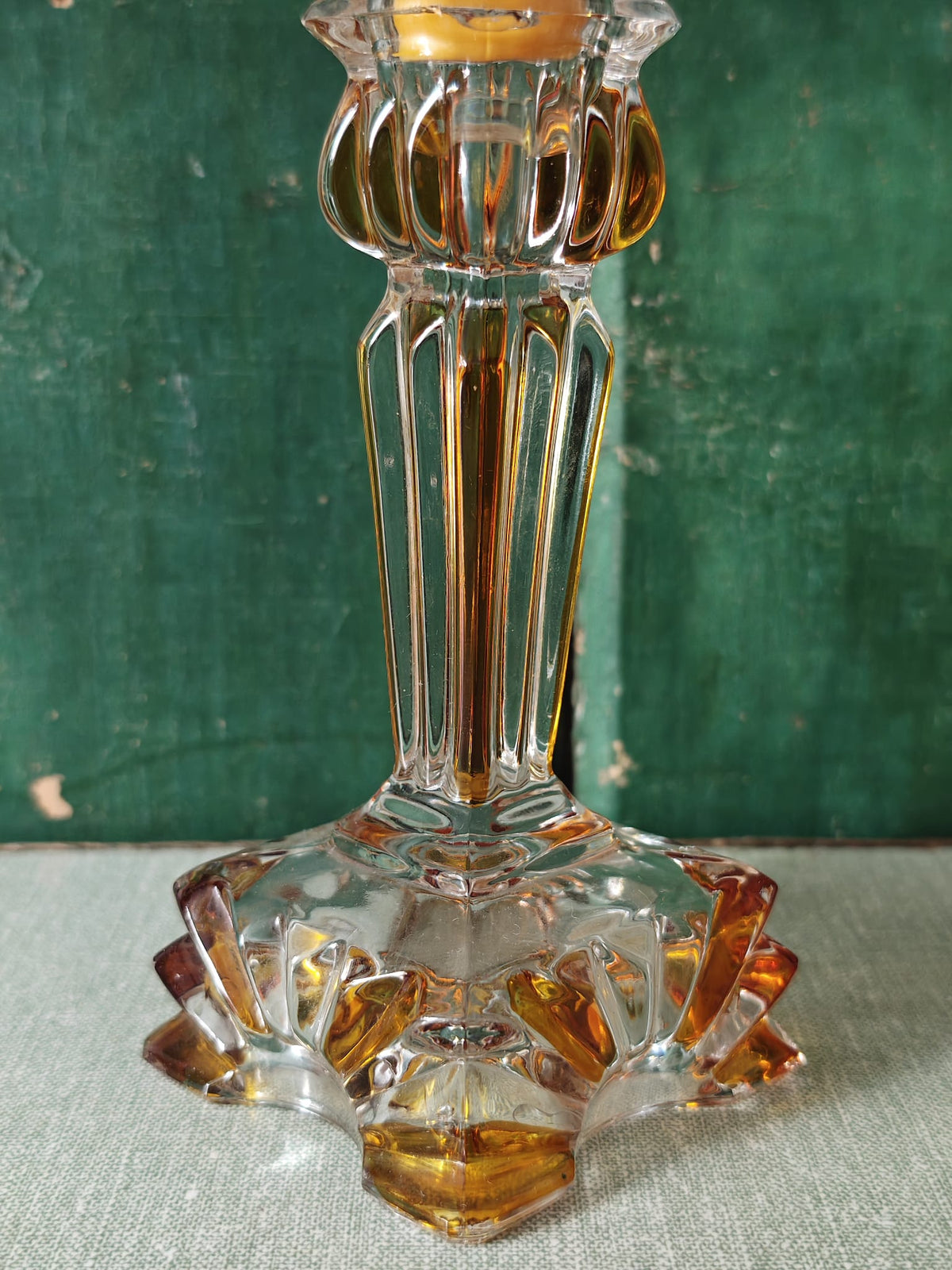 A vintage clear glass candlestick holder with amber-colored tinted accents.