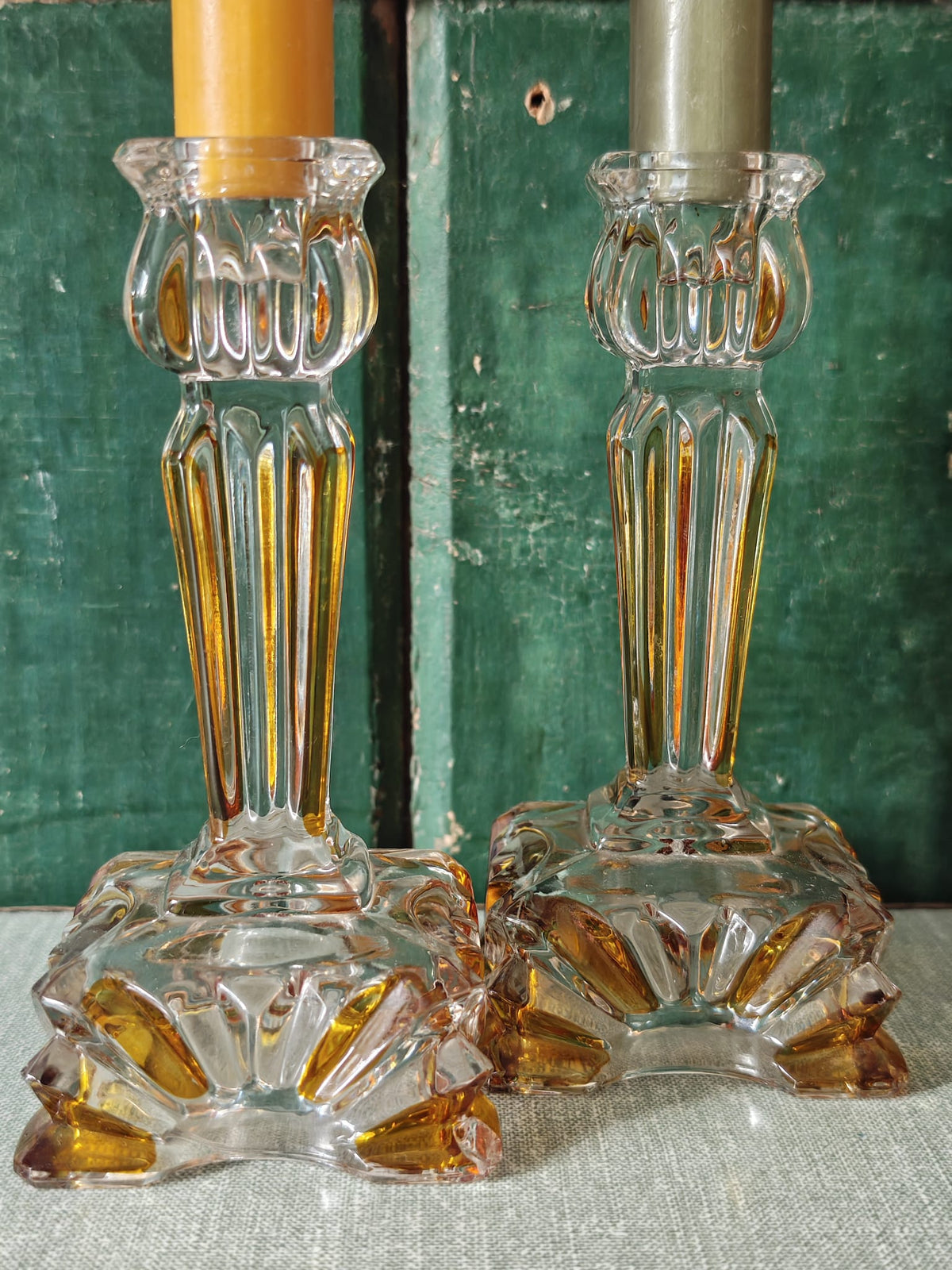 Two clear glass candlestick holders with ornate fluted bases and stems.