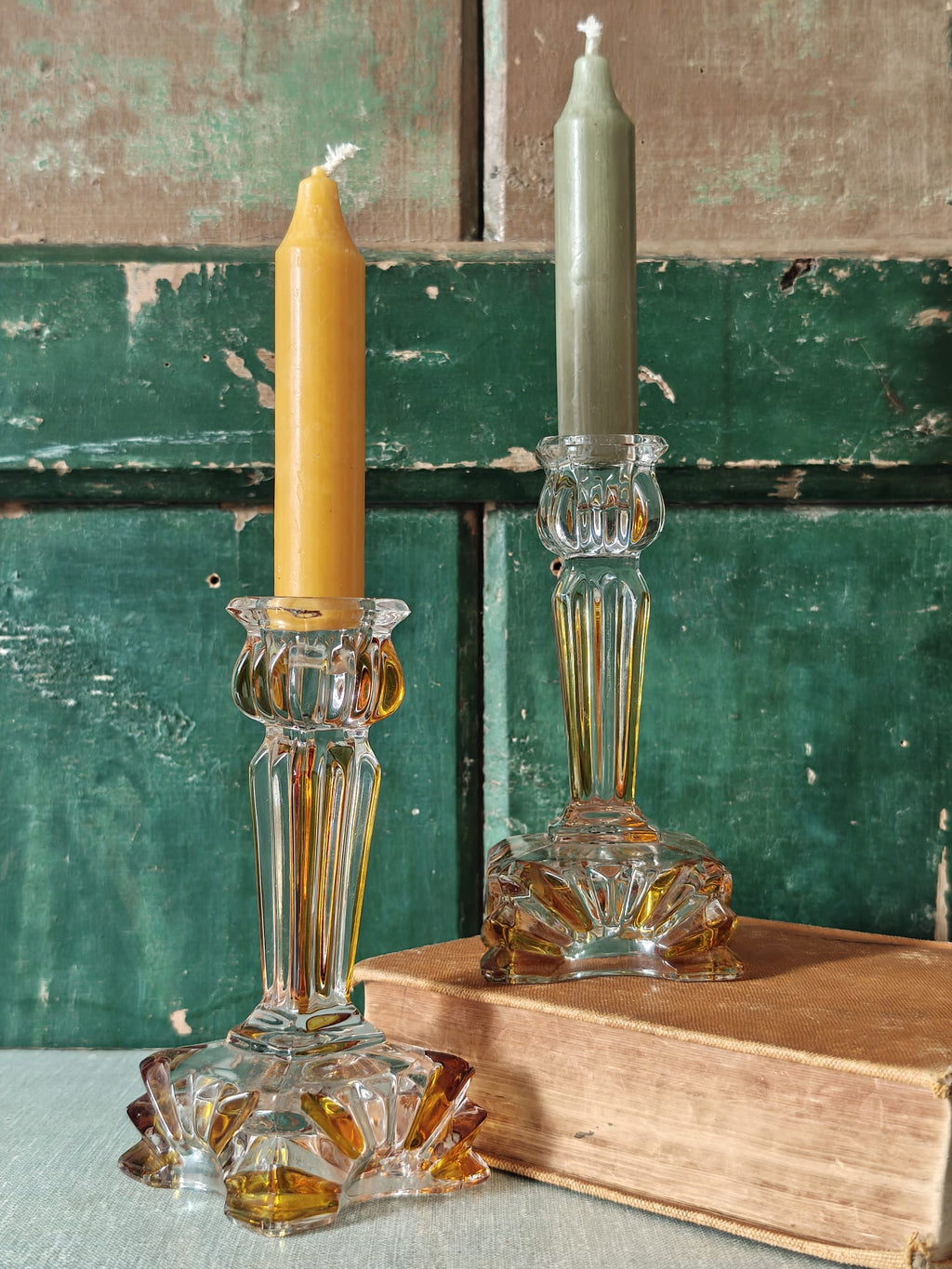 Two clear glass candlestick holders with amber-toned detailing.