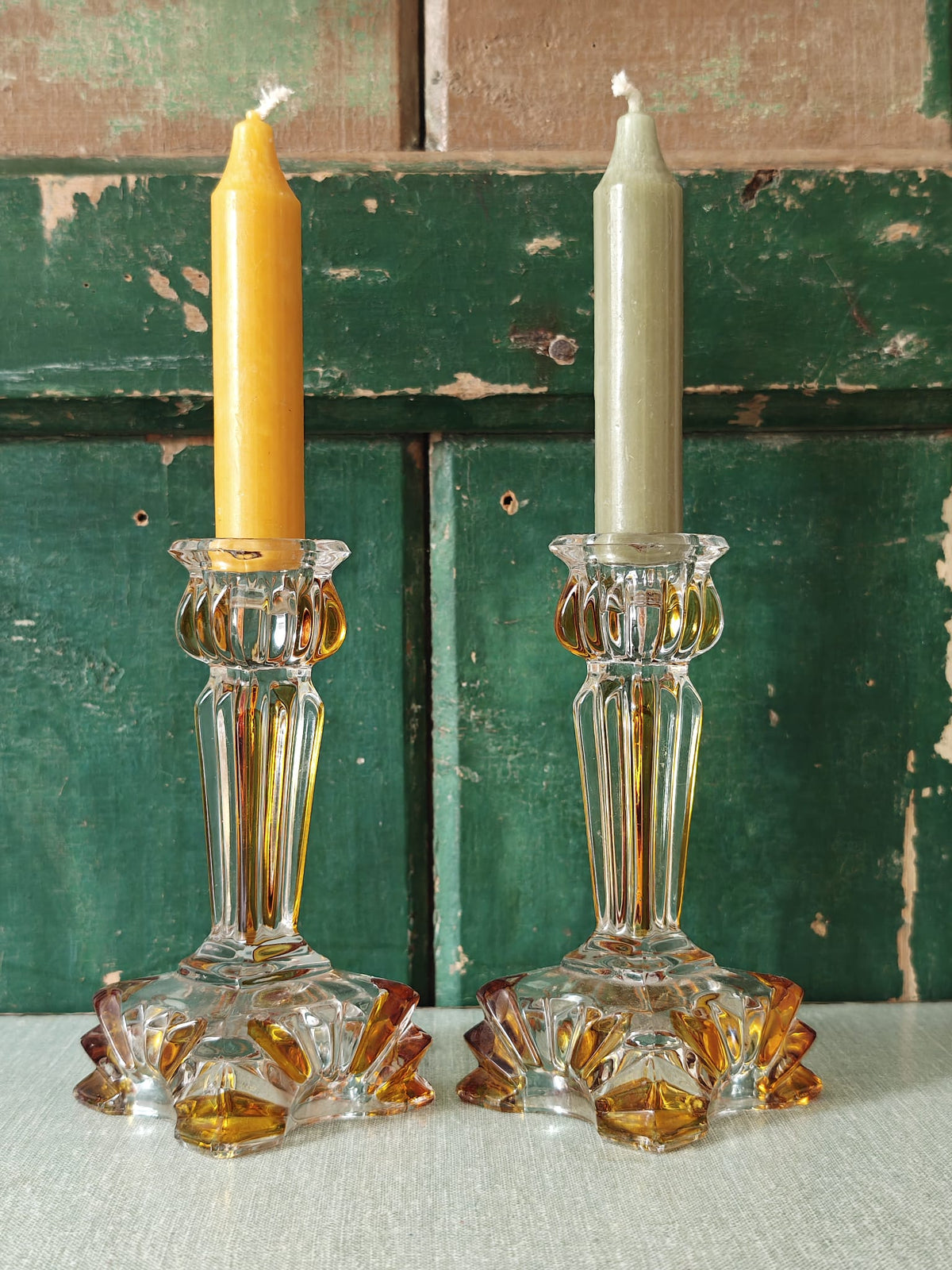 Two ornate clear glass candlestick holders with amber-colored accents.