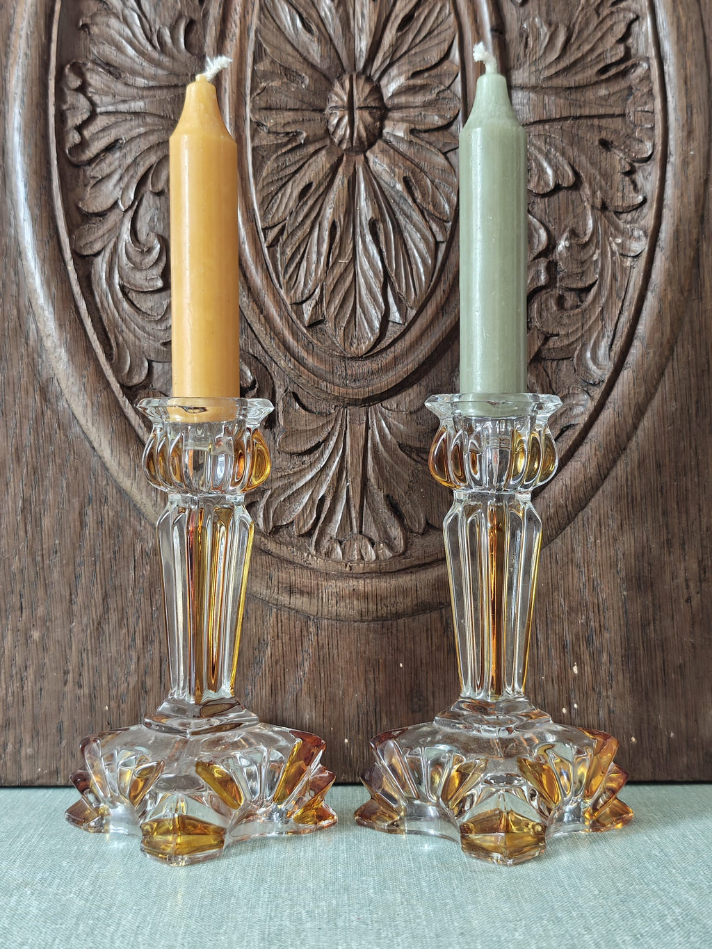 Two ornate clear glass candlestick holders with amber-colored accents.