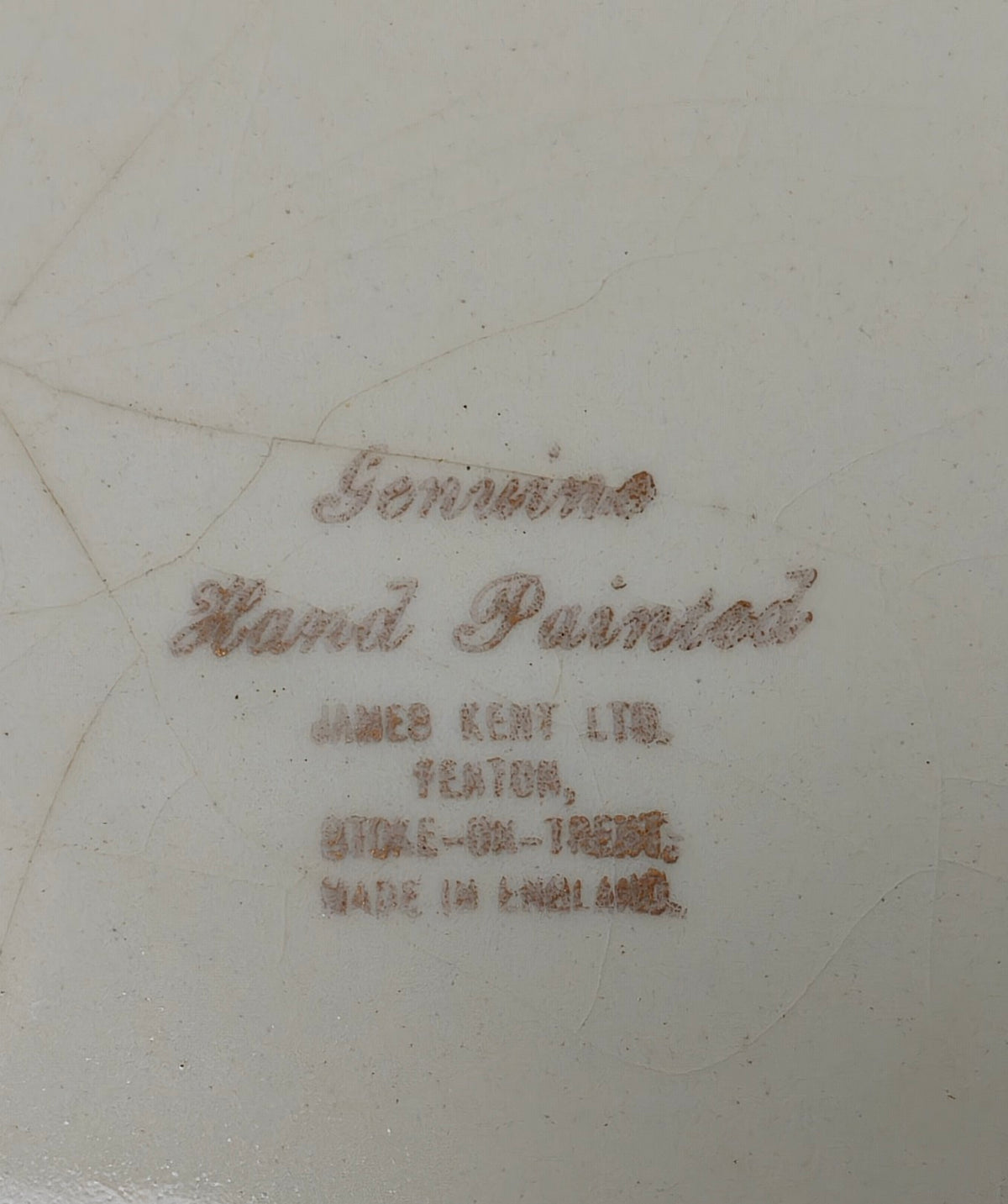 Close-up of the underside of a ceramic plate or dish showing printed authenticity text that reads 'Genuine Hand Painted' and 'JAMES KENT LTD. TEXTON, STORE-ON-TRESE, MADE IN ENGLAND.
