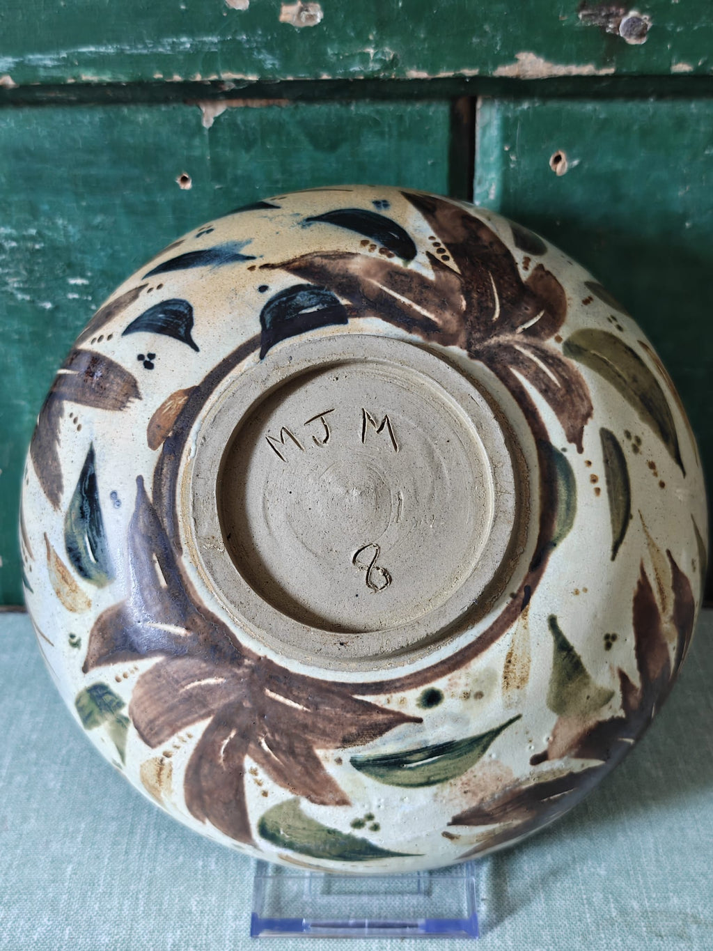 A handmade ceramic bowl with a hand-painted leaf pattern.