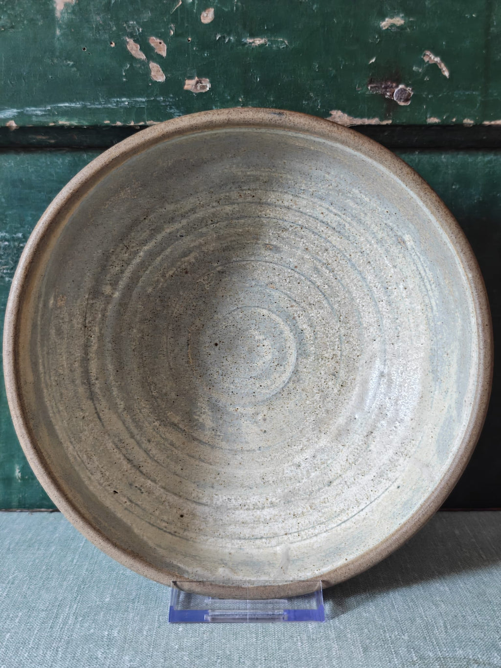 A large handmade ceramic bowl with a textured, speckled gray and beige glaze.