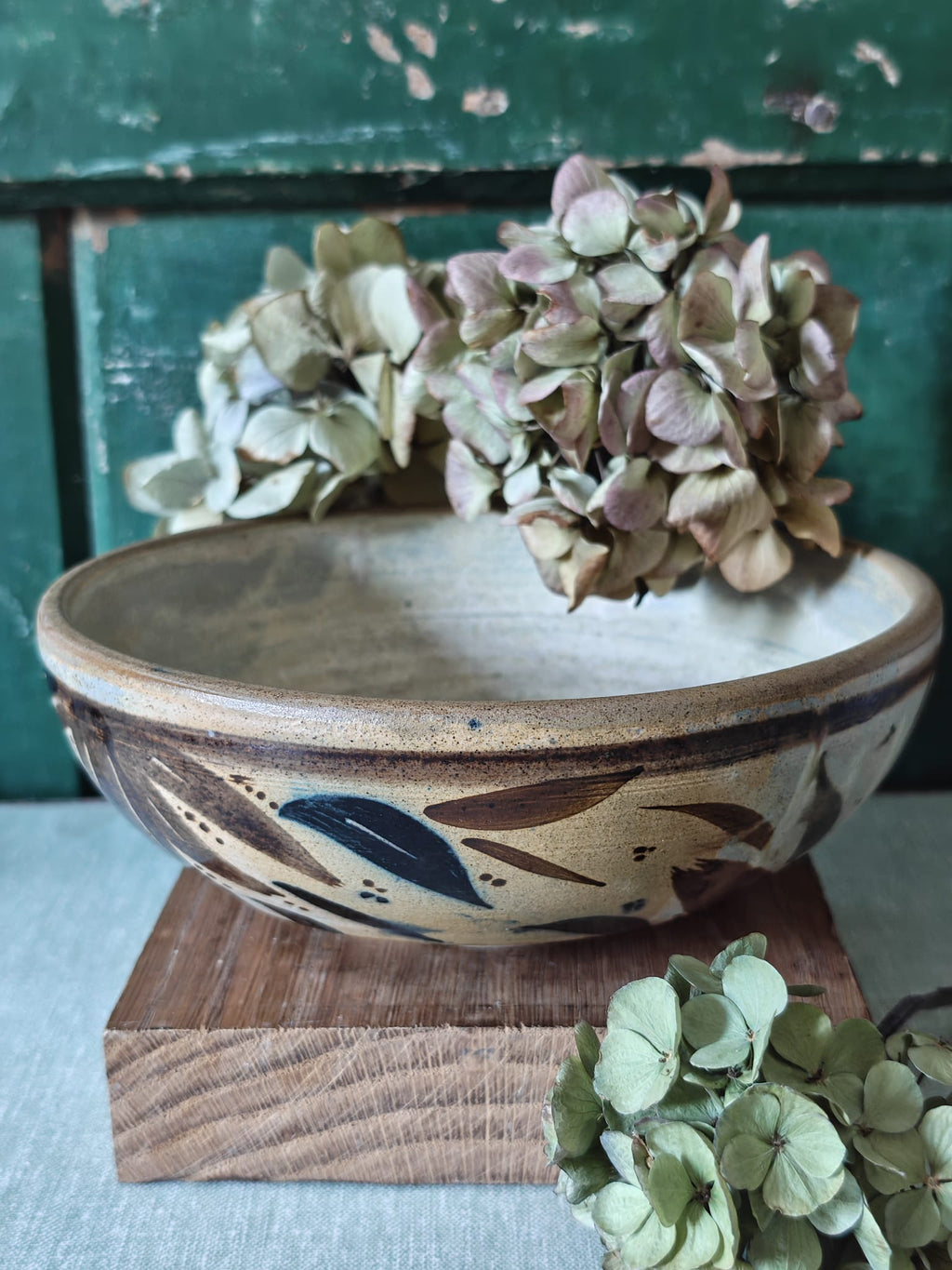 A handmade ceramic bowl with a rustic hand-painted leaf design.