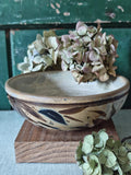 A handmade ceramic bowl with a rustic hand-painted leaf design.