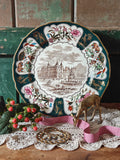 A decorative Christmas plate with a palace illustration and floral border.