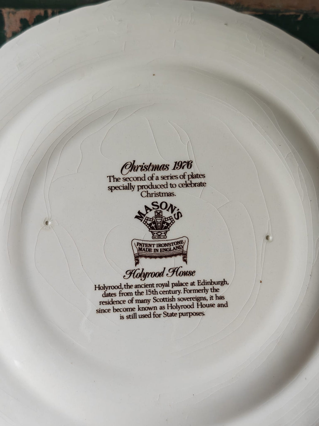 The back of a ceramic plate featuring printed black text and logos, including 'Christmas 1976', 'Mason's', and 'Holyrood House'.