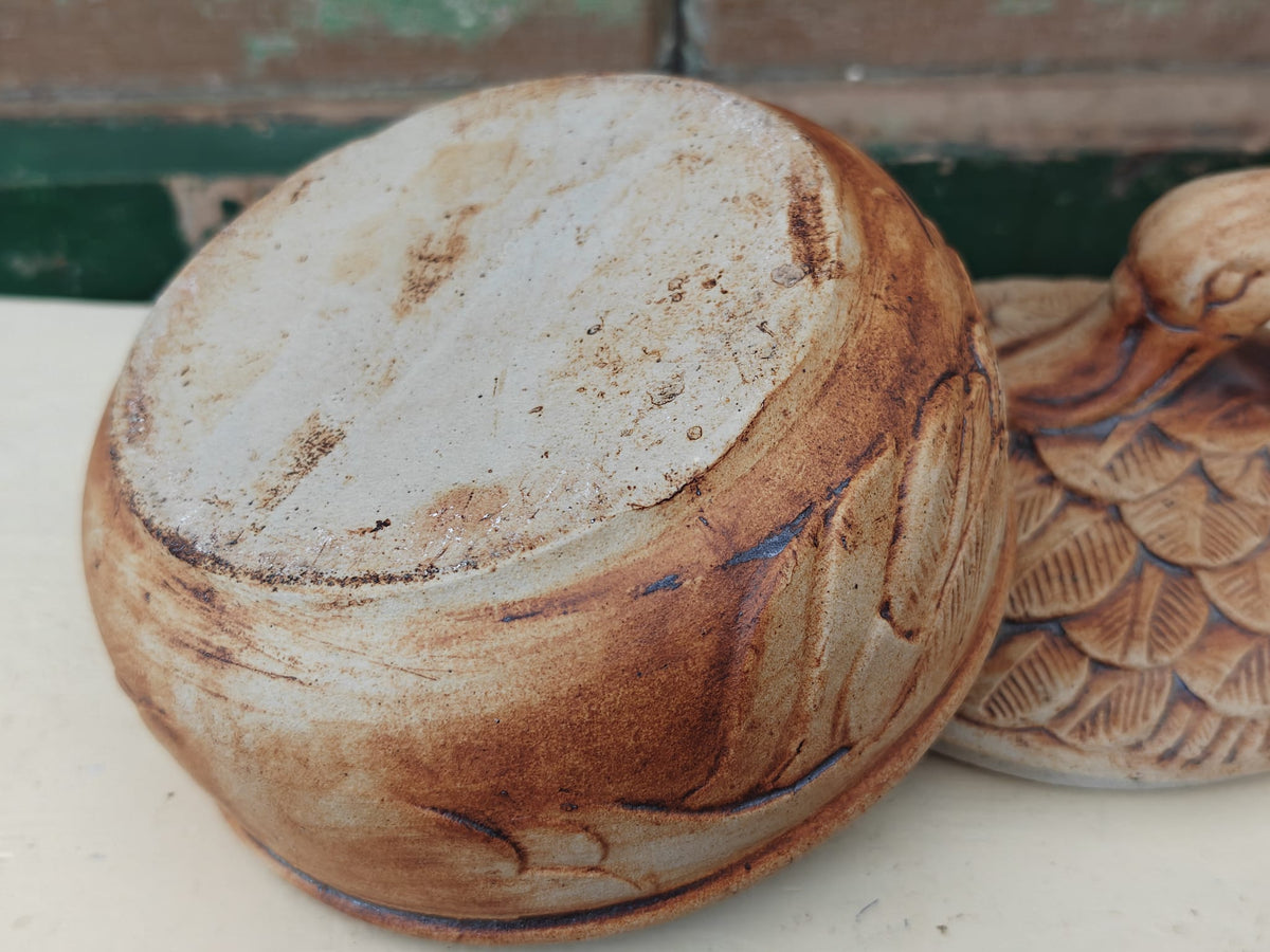A close-up of a rustic ceramic bowl with a textured, hand-painted finish.