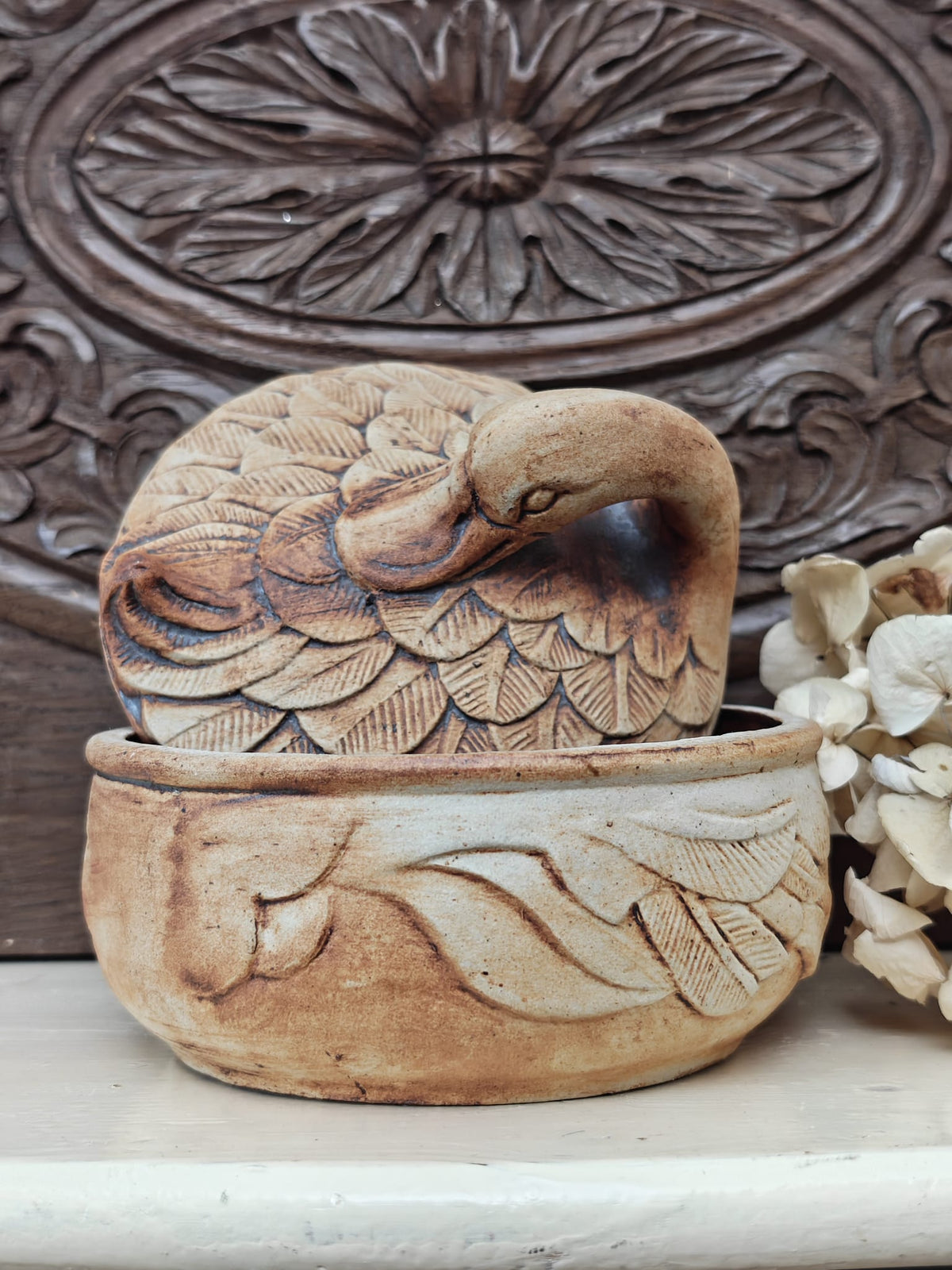 A small carved decorative ceramic container with a duck shaped lid.