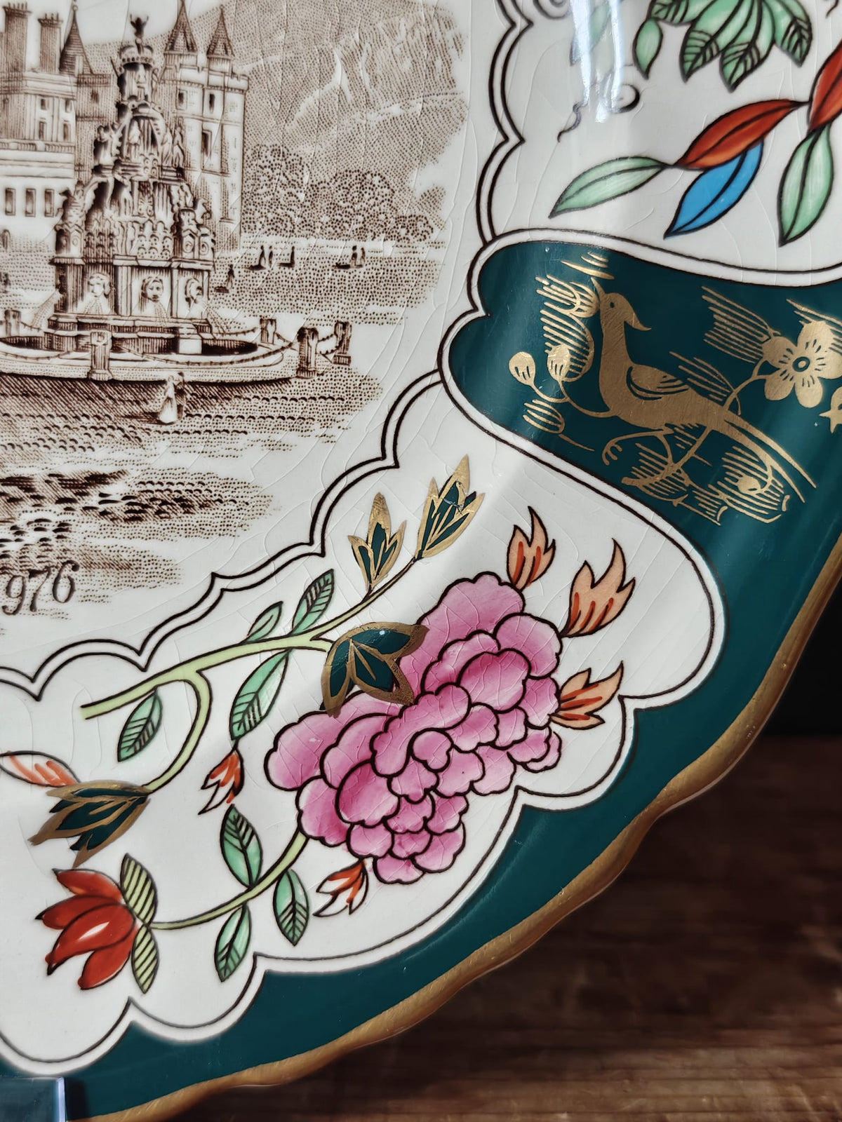 Close-up of an ornate ceramic plate featuring a brown architectural landscape print.