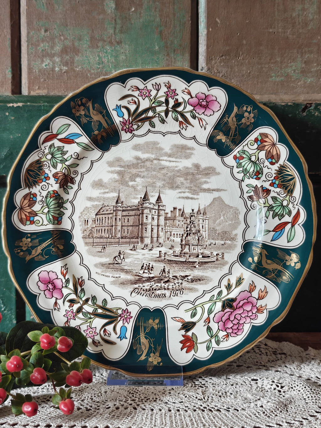 An ornate round Christmas plate with a floral border and central palace illustration.