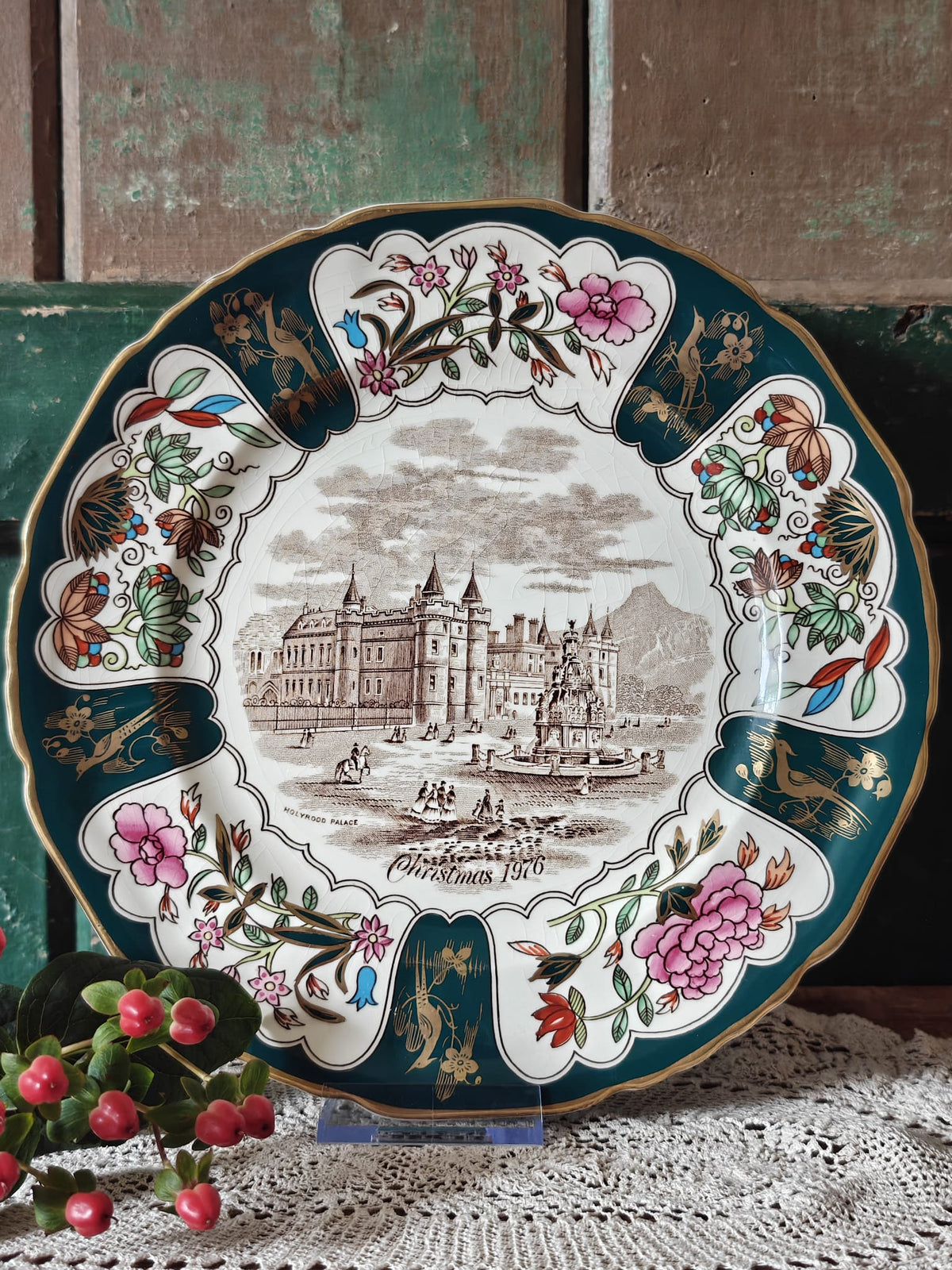 An ornate round Christmas plate with a floral border and central palace illustration.