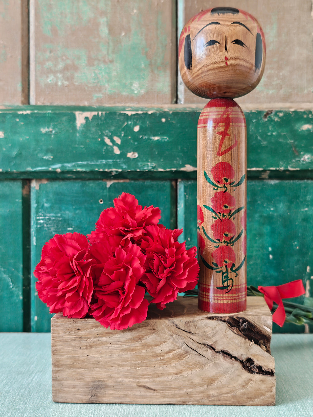 Wooden kokeshi doll with red flower decoration