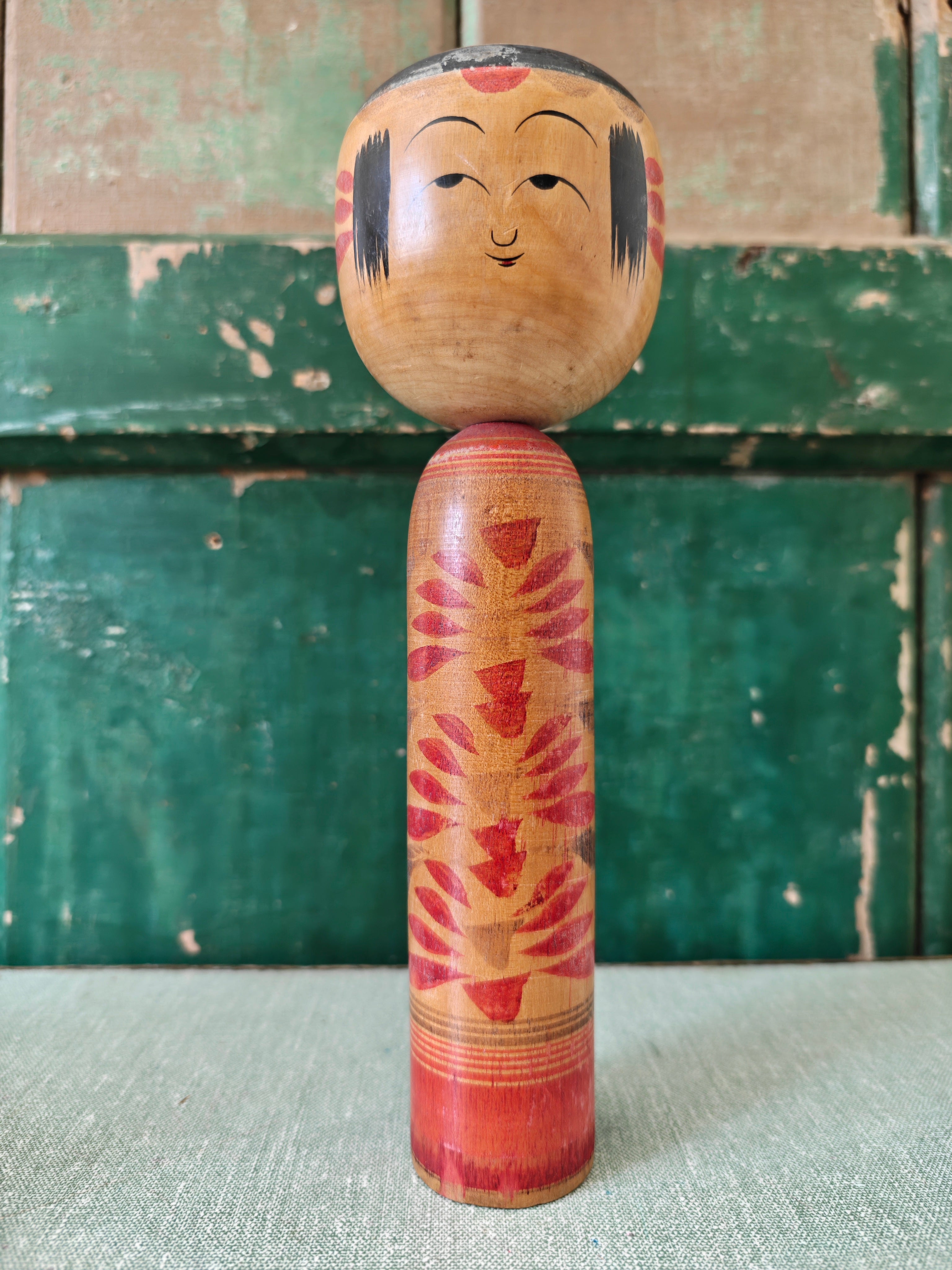 Vintage wooden kokeshi doll with floral pattern