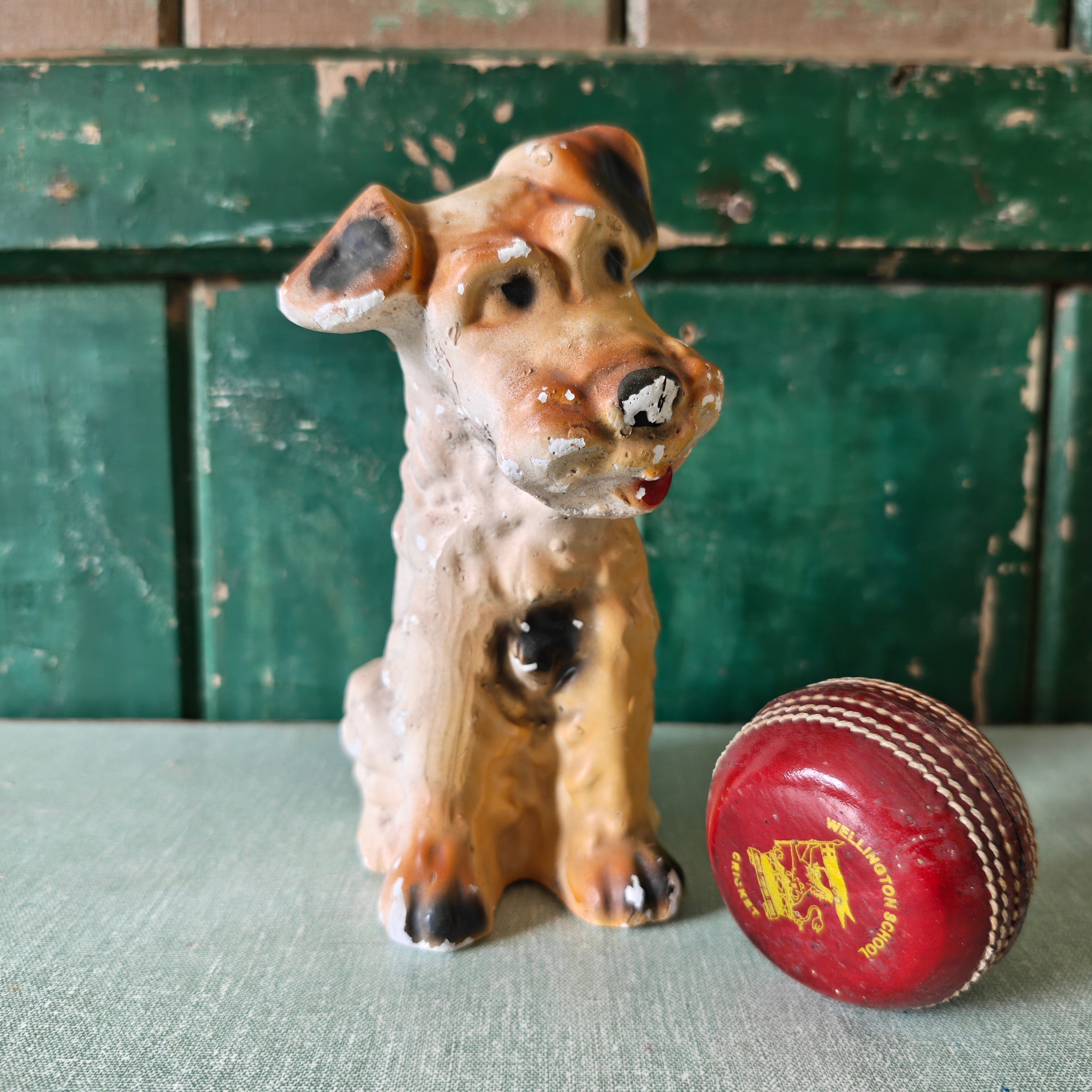 Vintage chalkware dog figurine with a cricket ball 