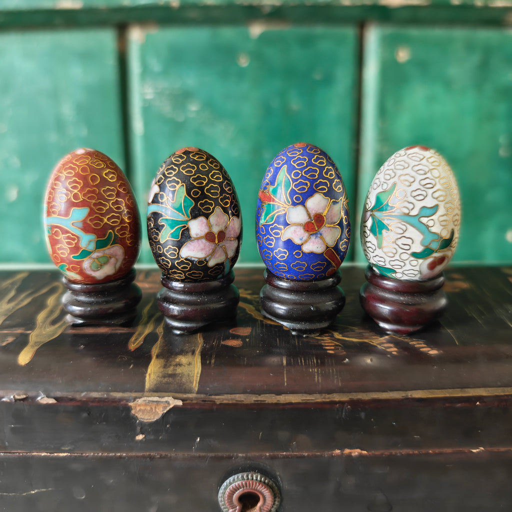Four intricately patterned coloured eggs on stands 