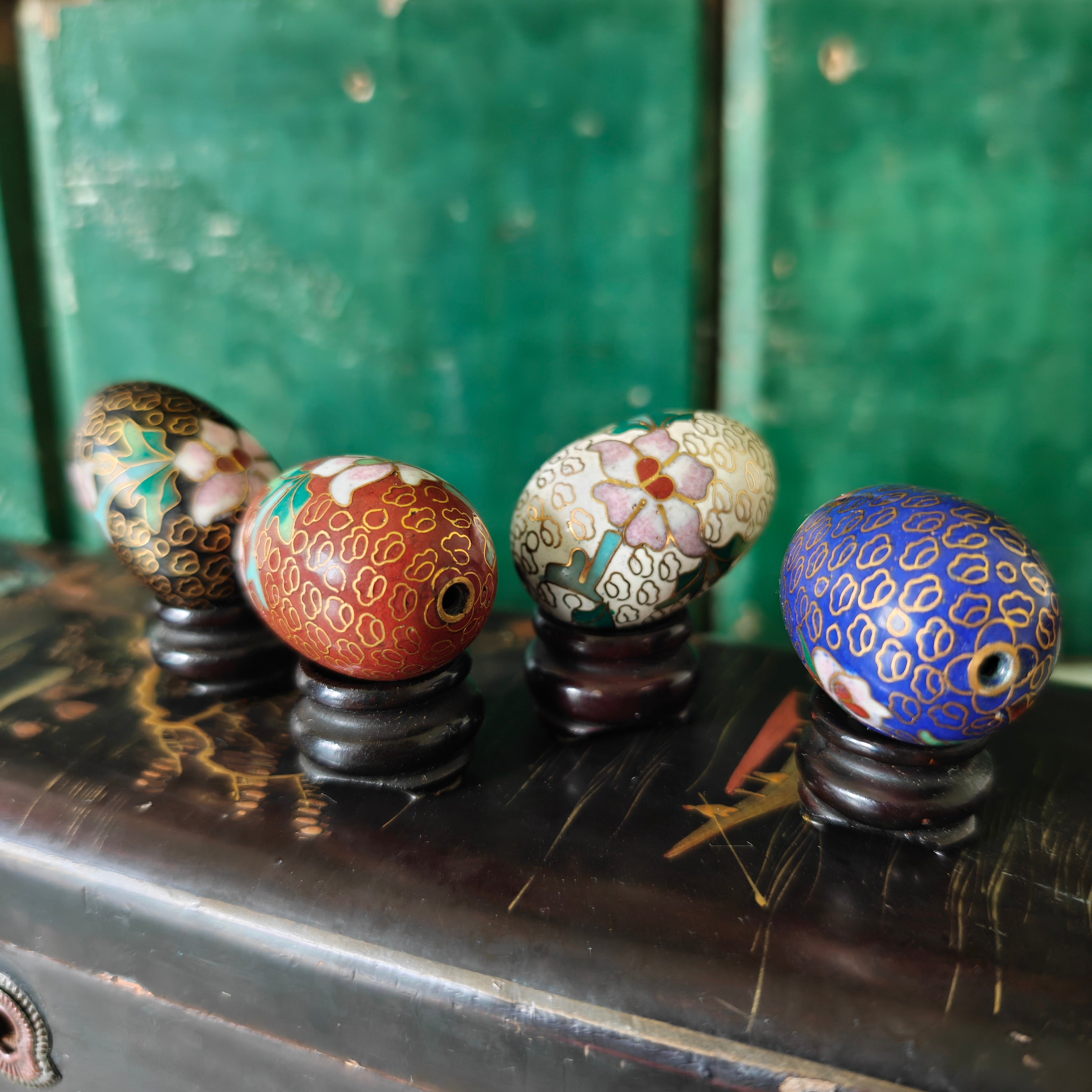 Four intricately patterned coloured eggs on stands 