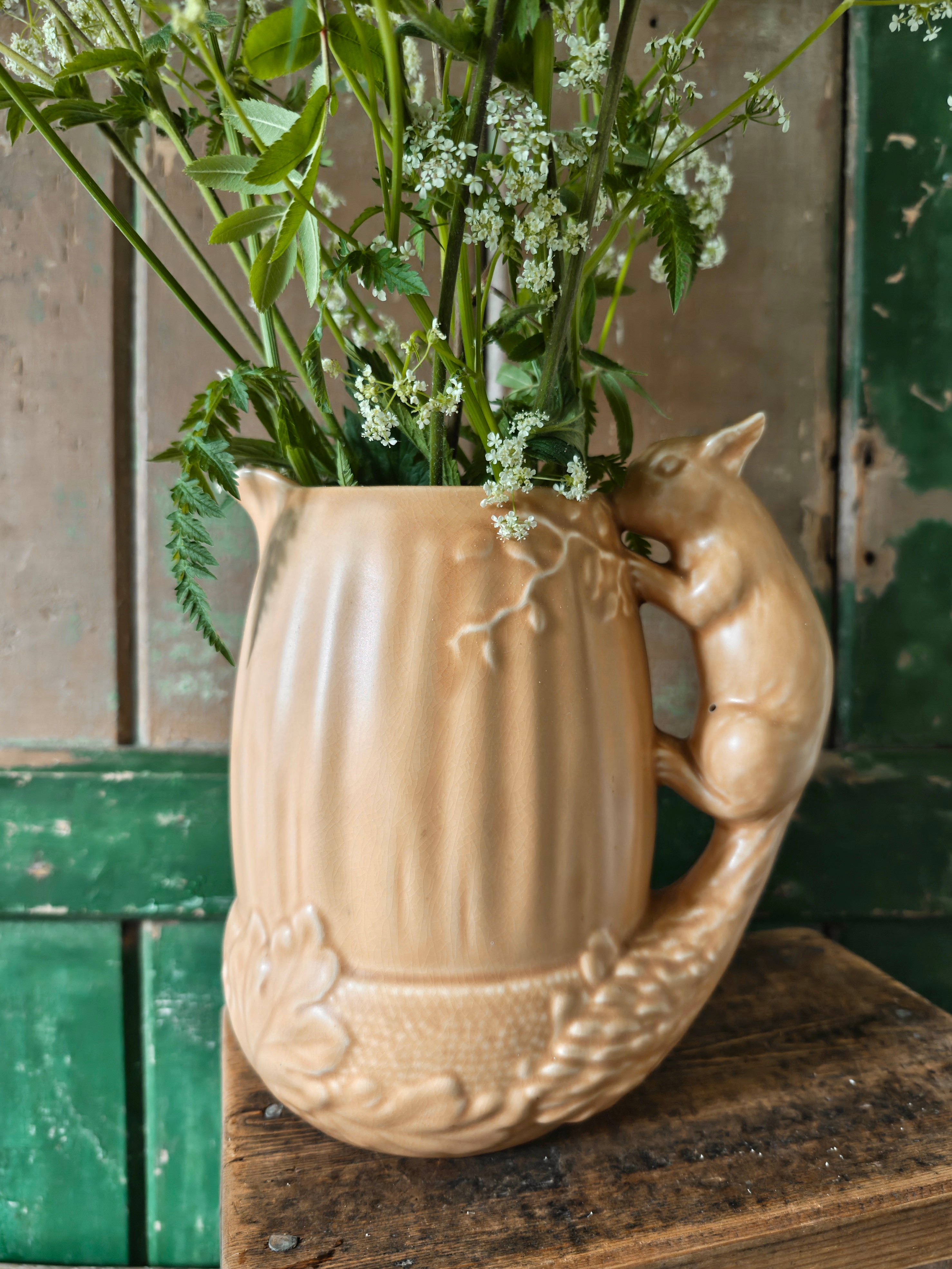 Brown ceramic pitcher in acorn shape with a squirrel design handle