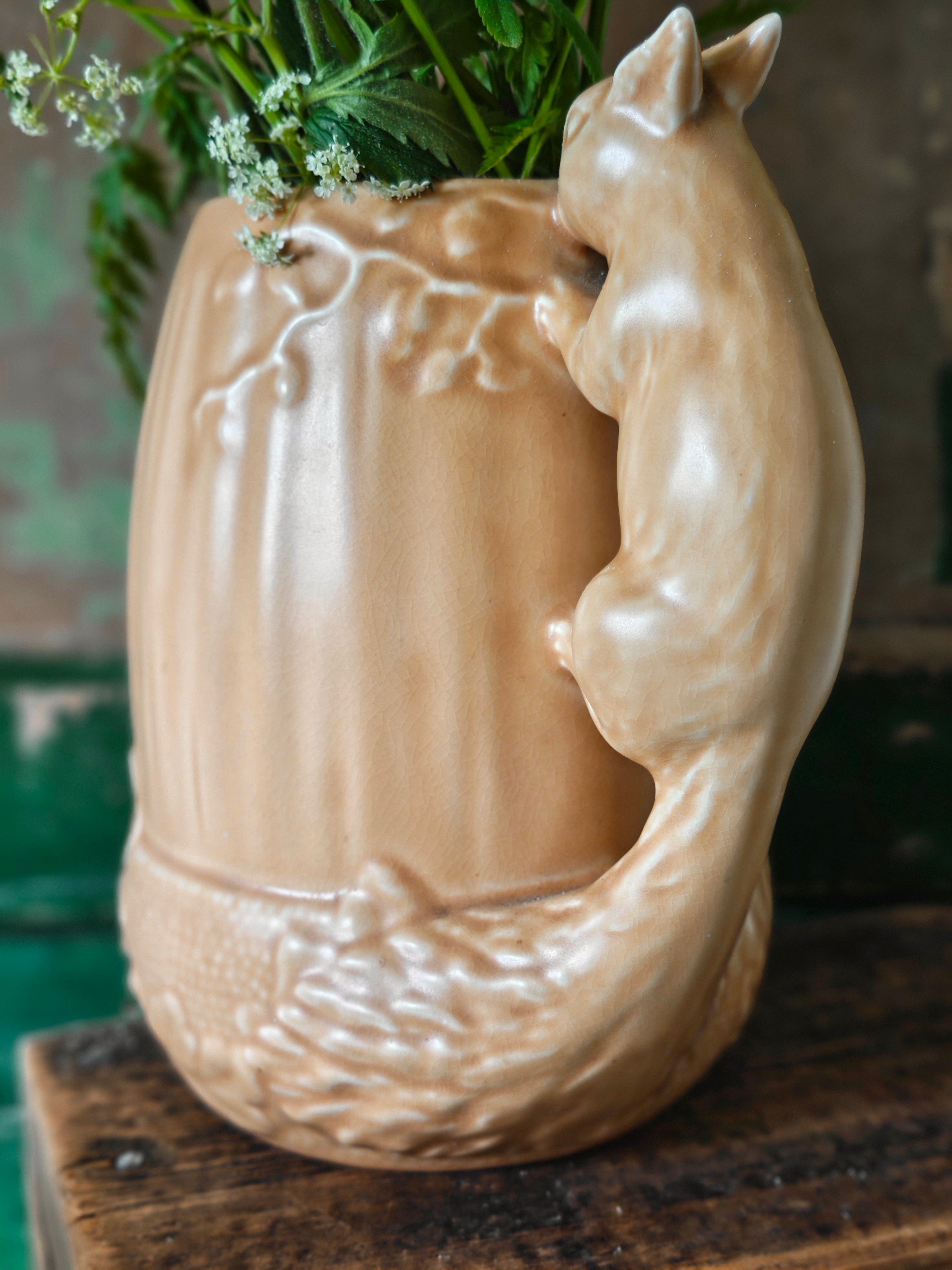 Brown ceramic pitcher in acorn shape with a squirrel design handle