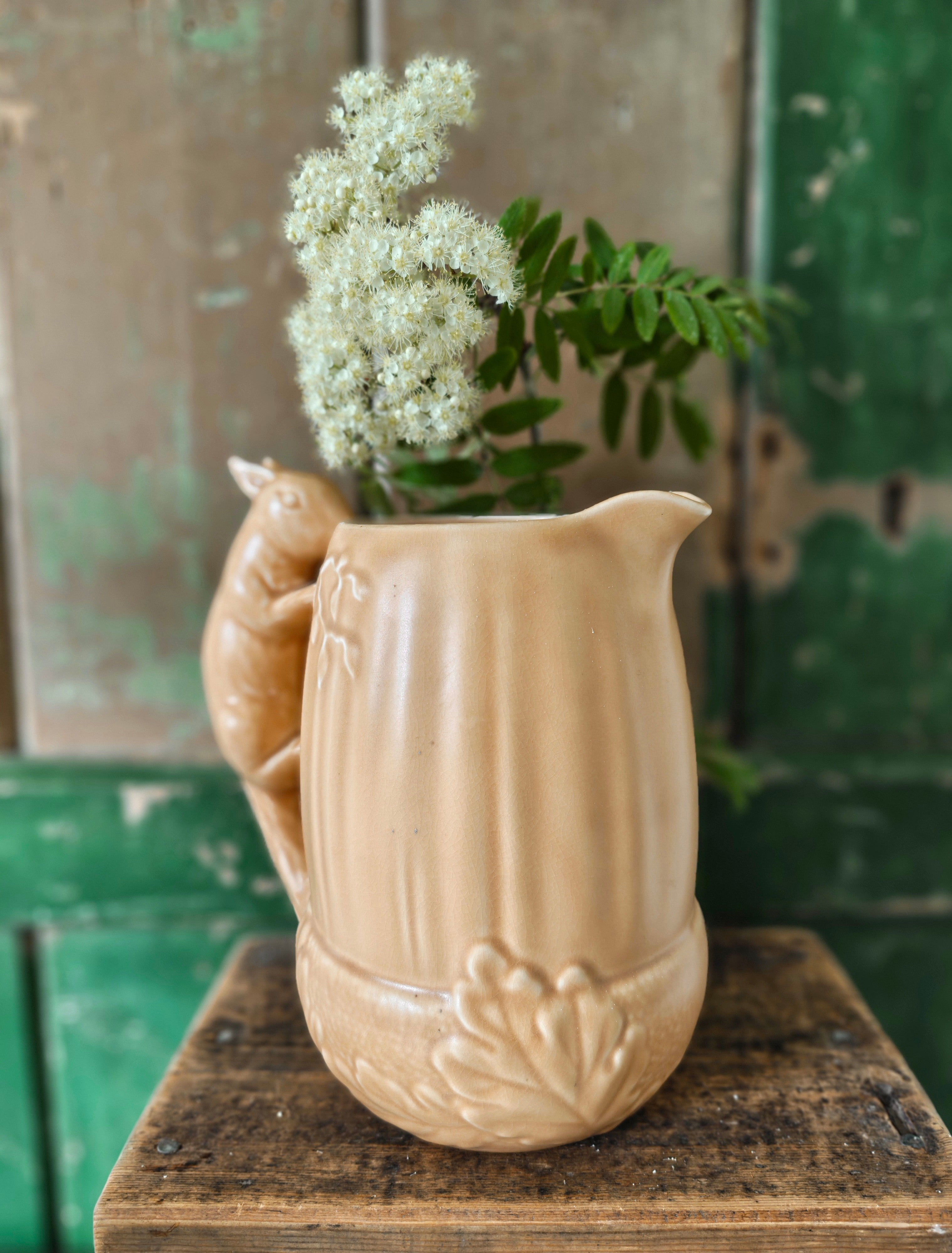 Brown ceramic pitcher in acorn shape with a squirrel design handle