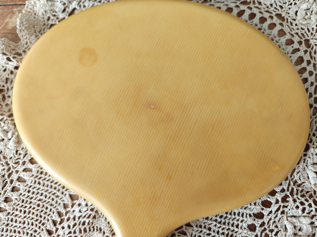 Close-up of the back of a vintage ivory coloured oval hand mirror