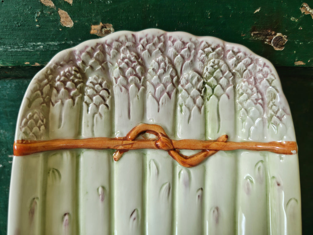 Close-up of decorative green ceramic asparagus platter showing asparagus tips and string effect