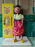 Traditional marionette puppet with a yellow box featuring illustrations of similar puppets in the background.