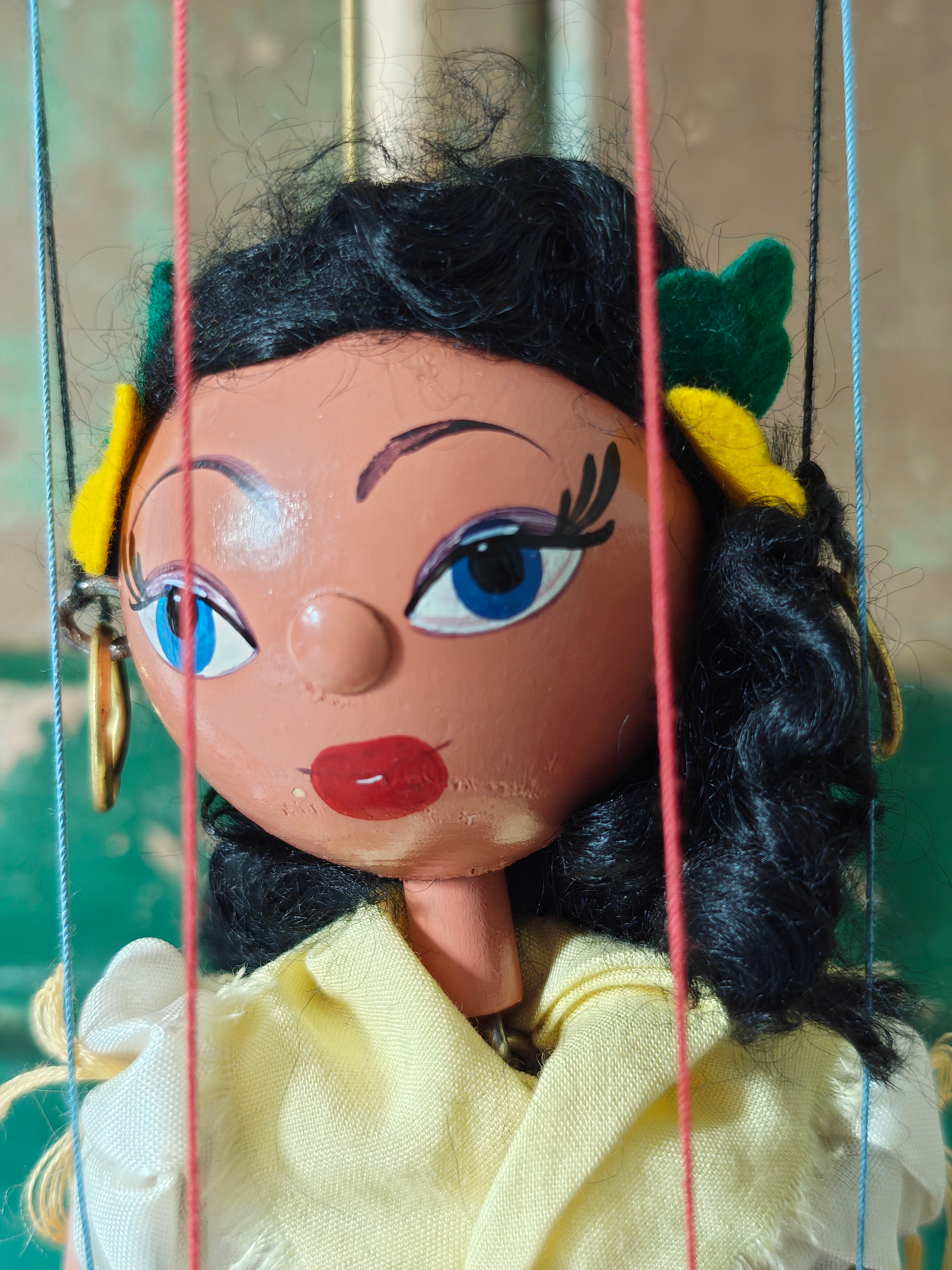 Close-up of a marionette with detailed facial features and colorful hair accessories.