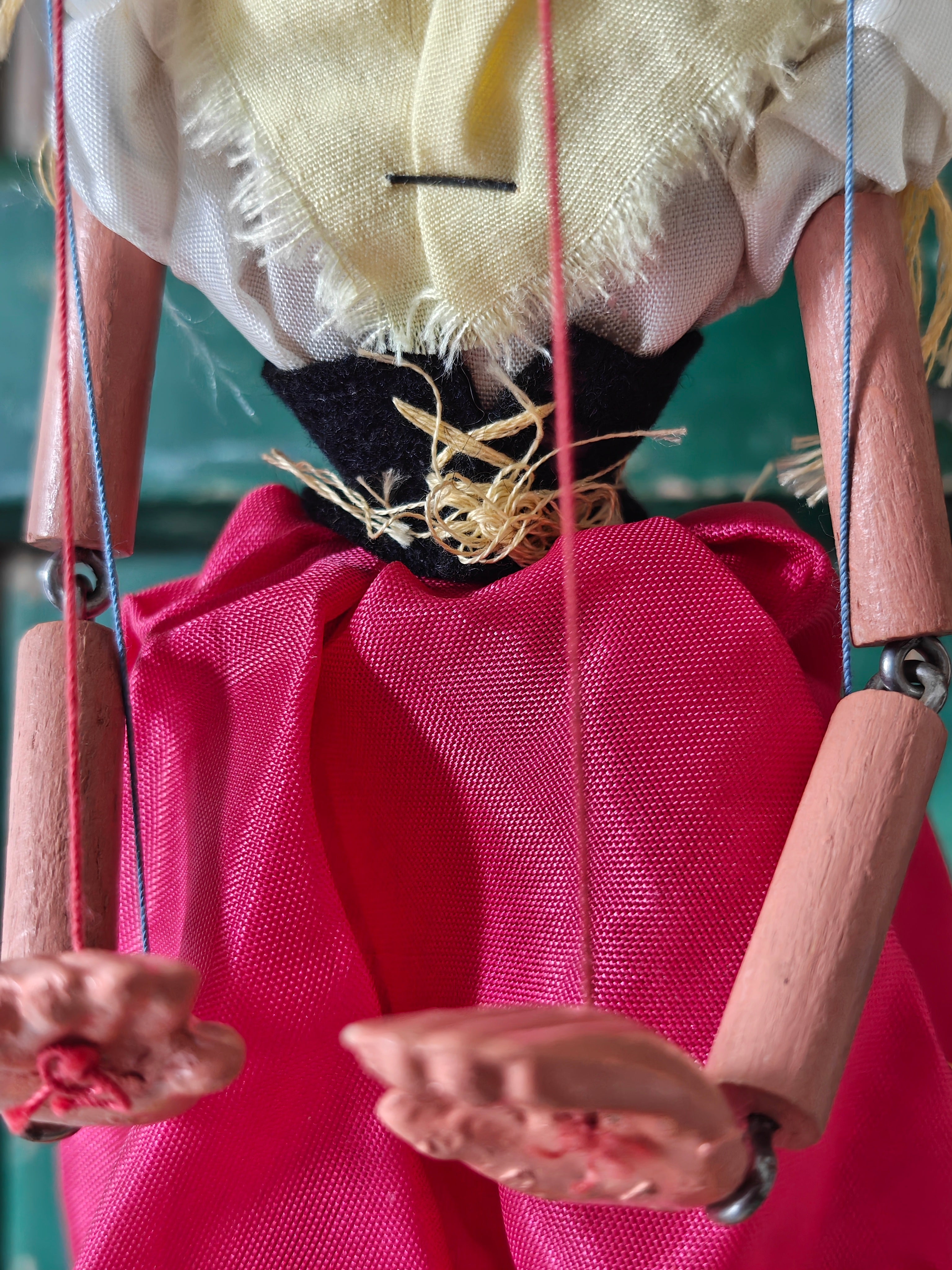 Close-up of a marionette with a pink dress and wooden arms and legs.