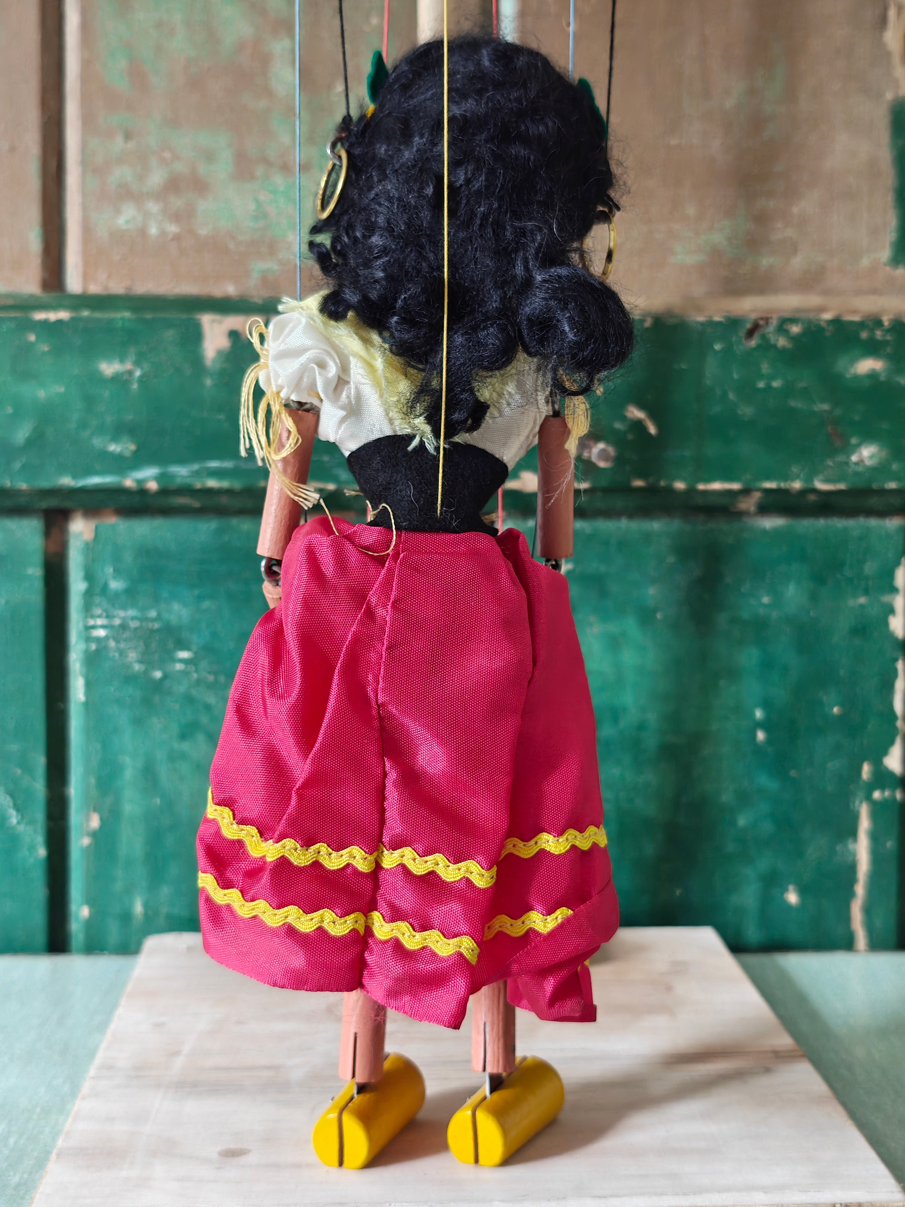 Puppet with black hair, pink dress with yellow trim, and yellow shoes 