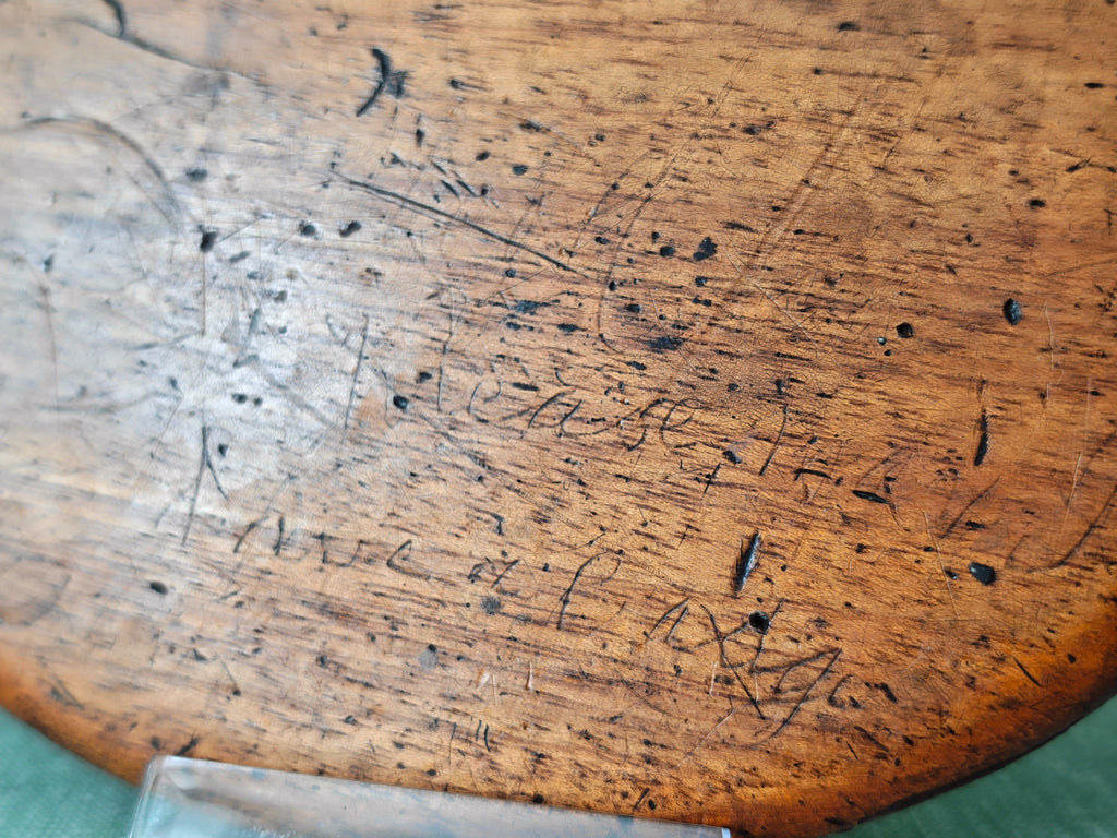 Close-up of scratched writing on the back of an antique wooden oval hand mirror 