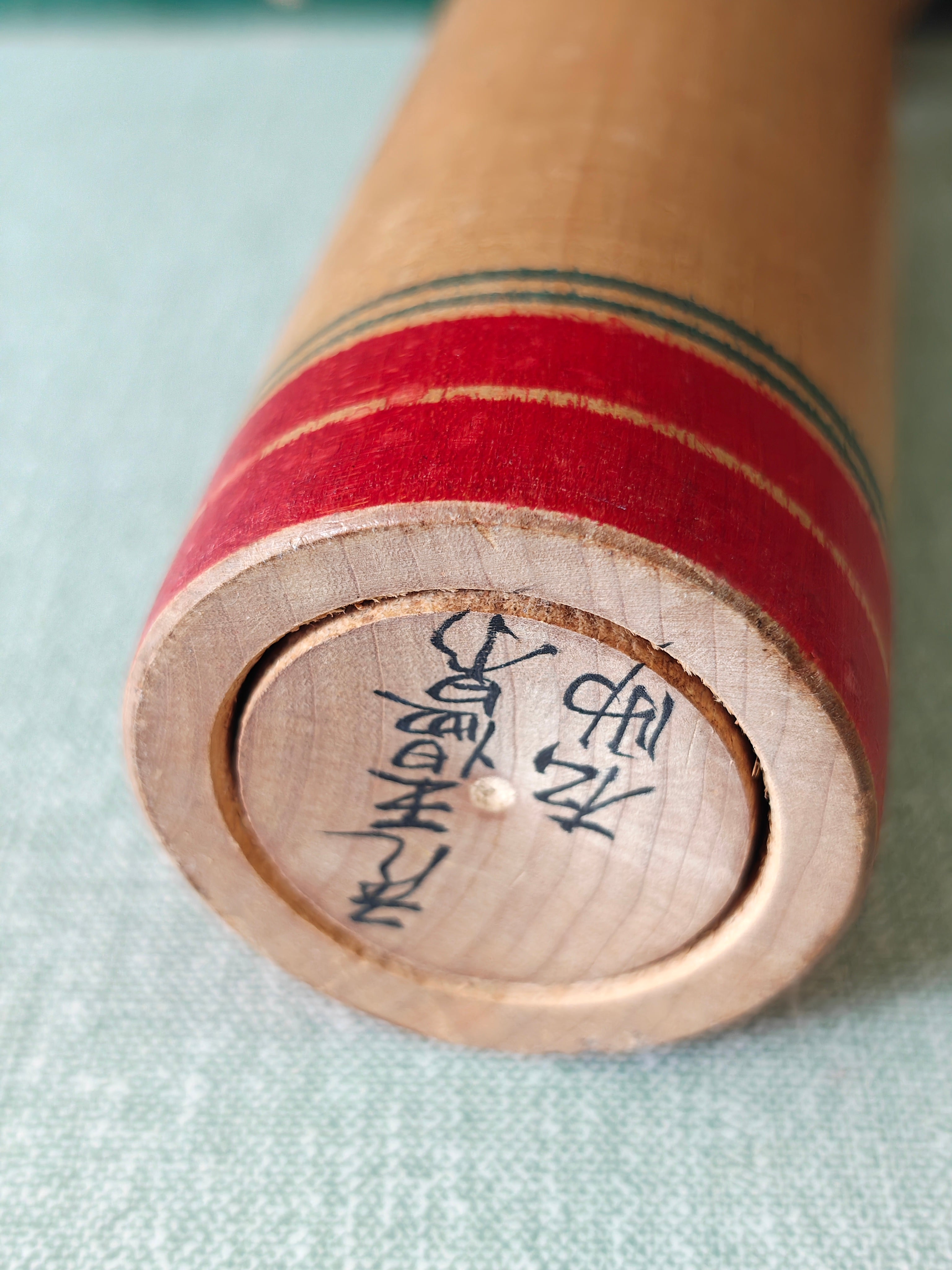 Artist's signature on the base of a Japanese vintage wooden Kokeshi doll
