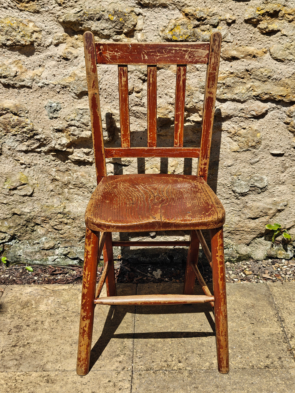 A rustic wooden chair with a distressed reddish-brown finish