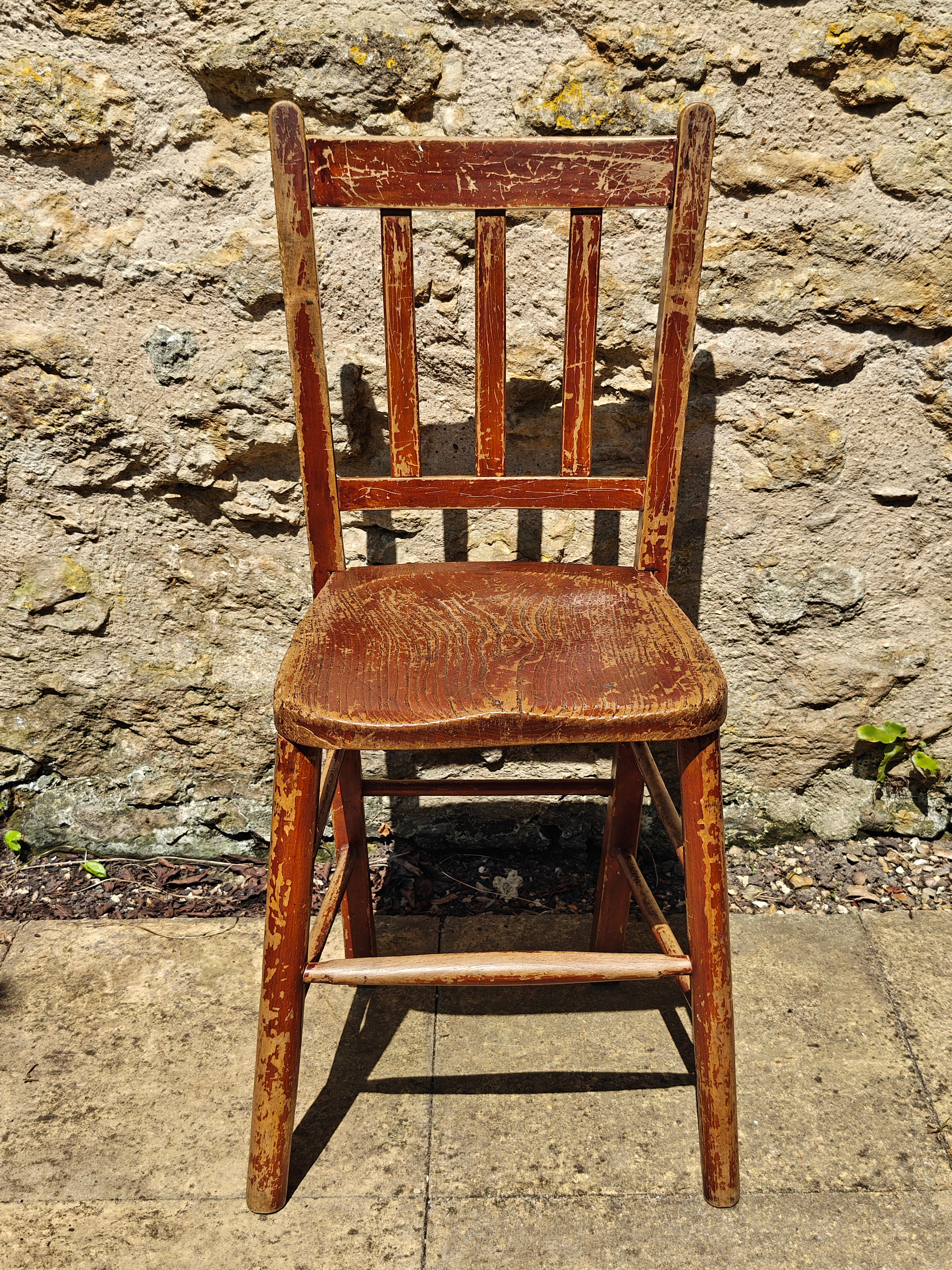 A rustic wooden chair with a distressed reddish-brown finish