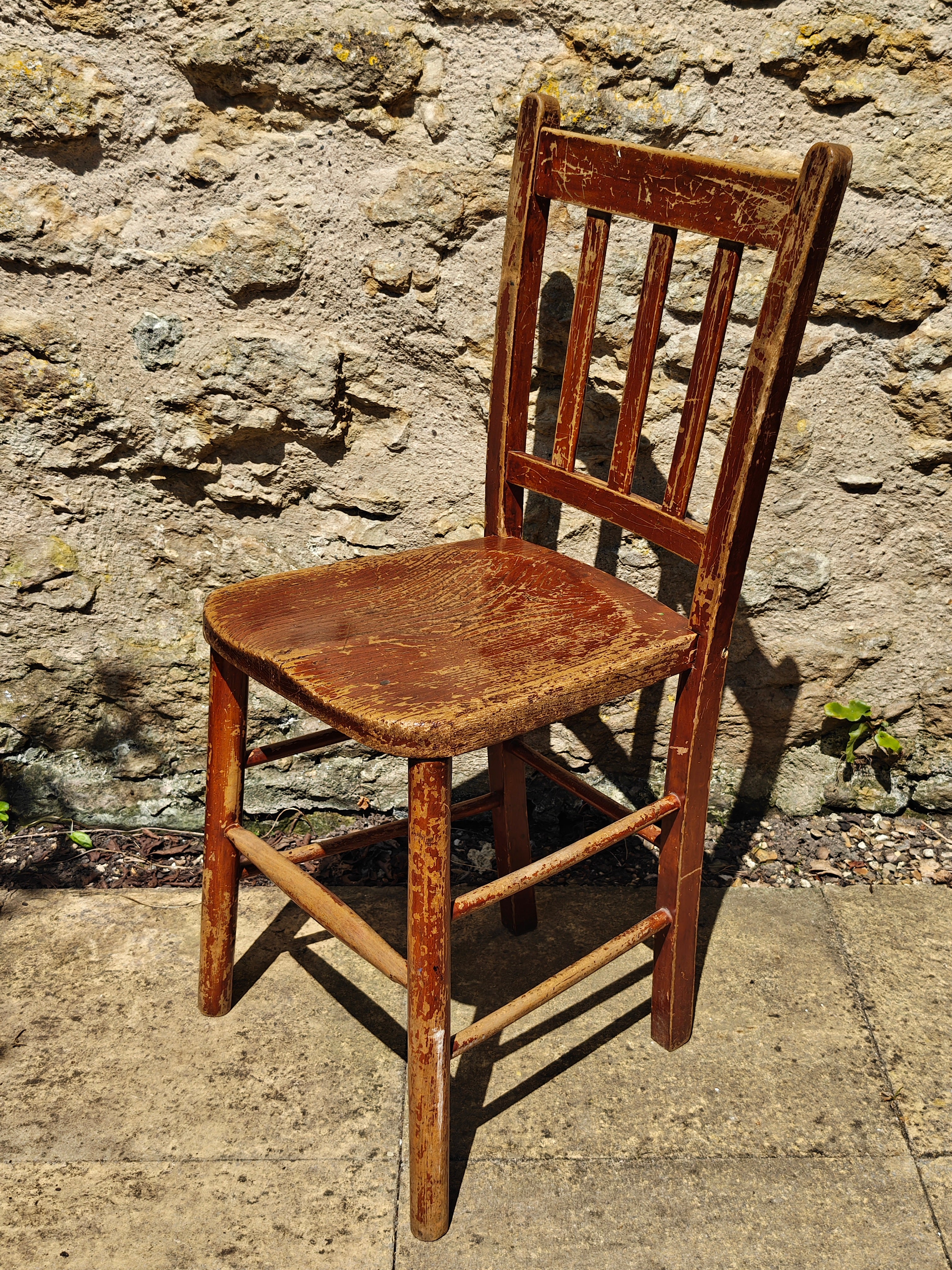 A rustic wooden chair with a distressed reddish-brown finish