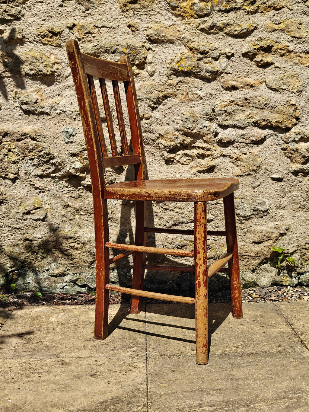 A rustic wooden chair with a distressed reddish-brown finish