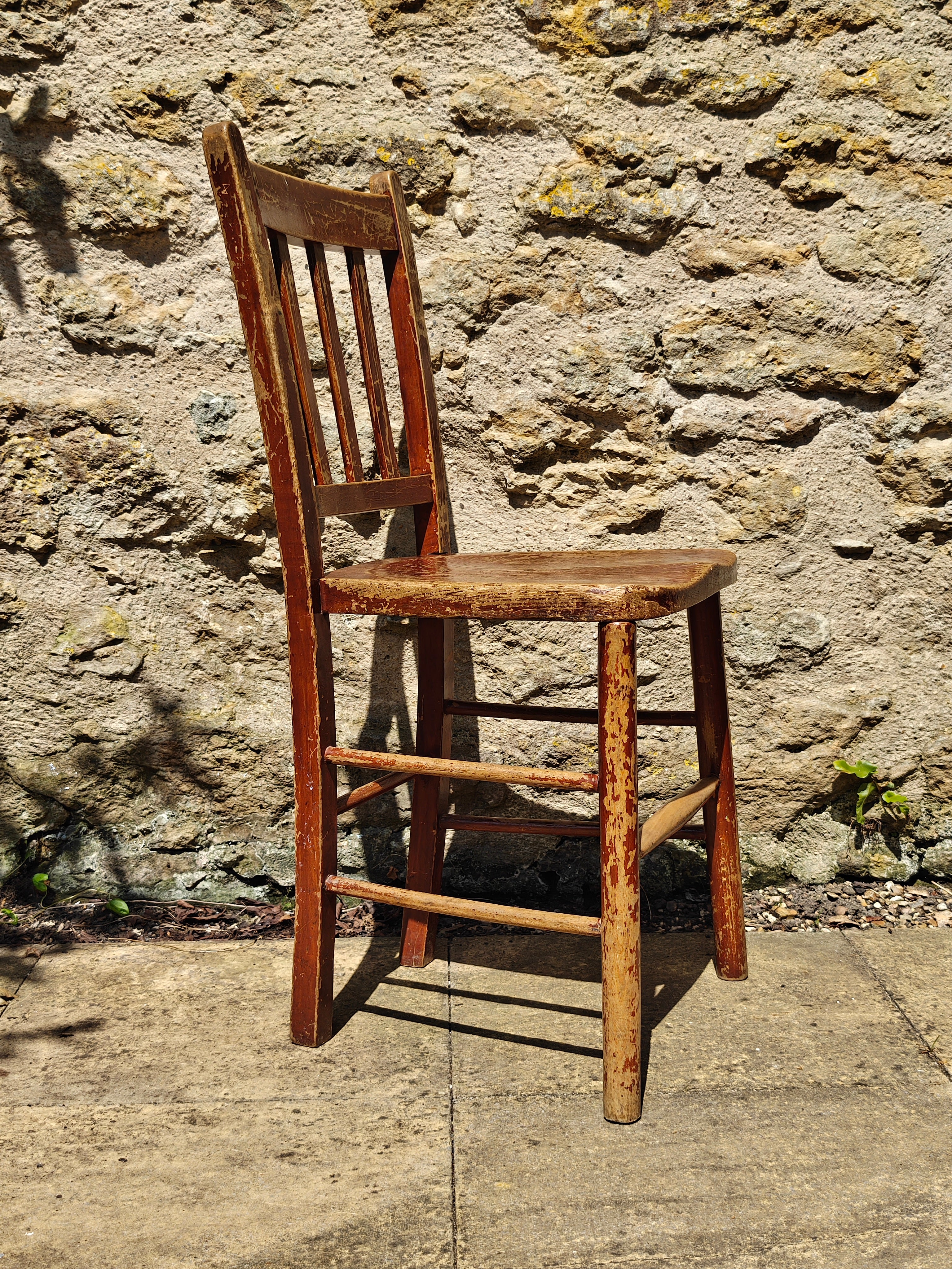 A rustic wooden chair with a distressed reddish-brown finish