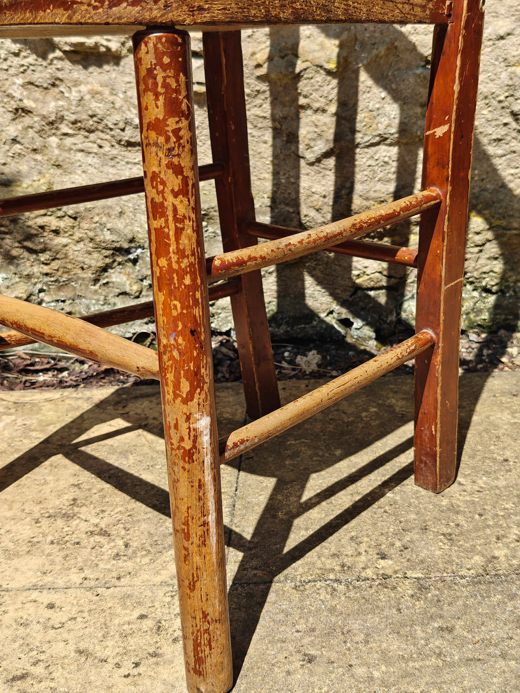 Close-up of the legs of a rustic wooden chair with a distressed reddish-brown finish