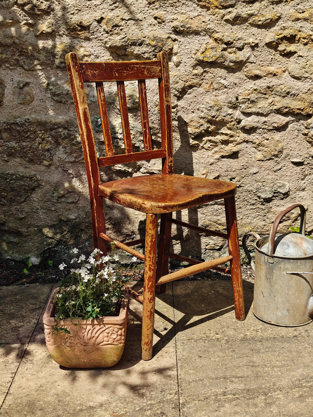 A rustic wooden chair with a distressed reddish-brown finish