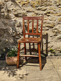 A rustic wooden chair with a distressed reddish-brown finish