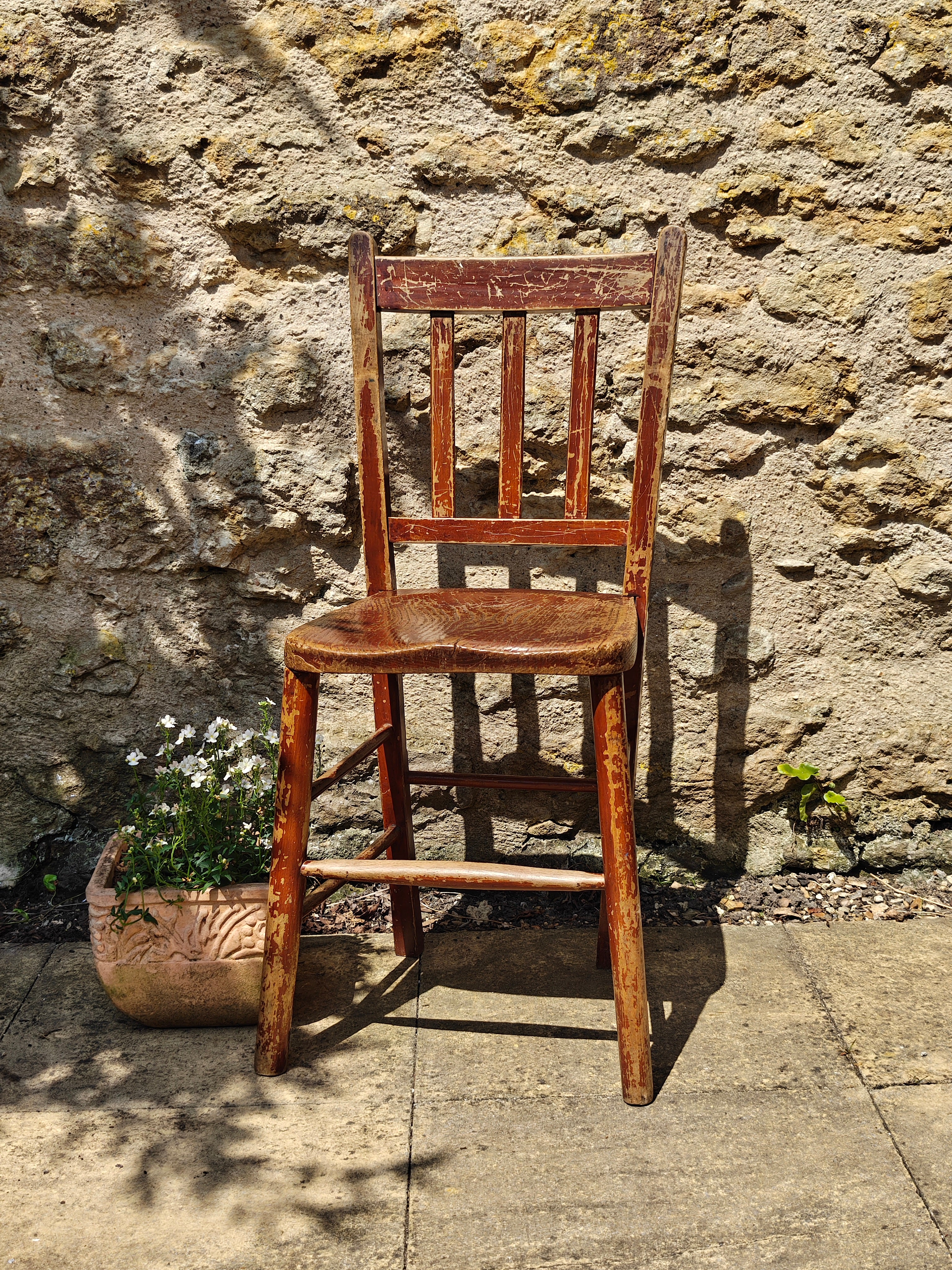 A rustic wooden chair with a distressed reddish-brown finish